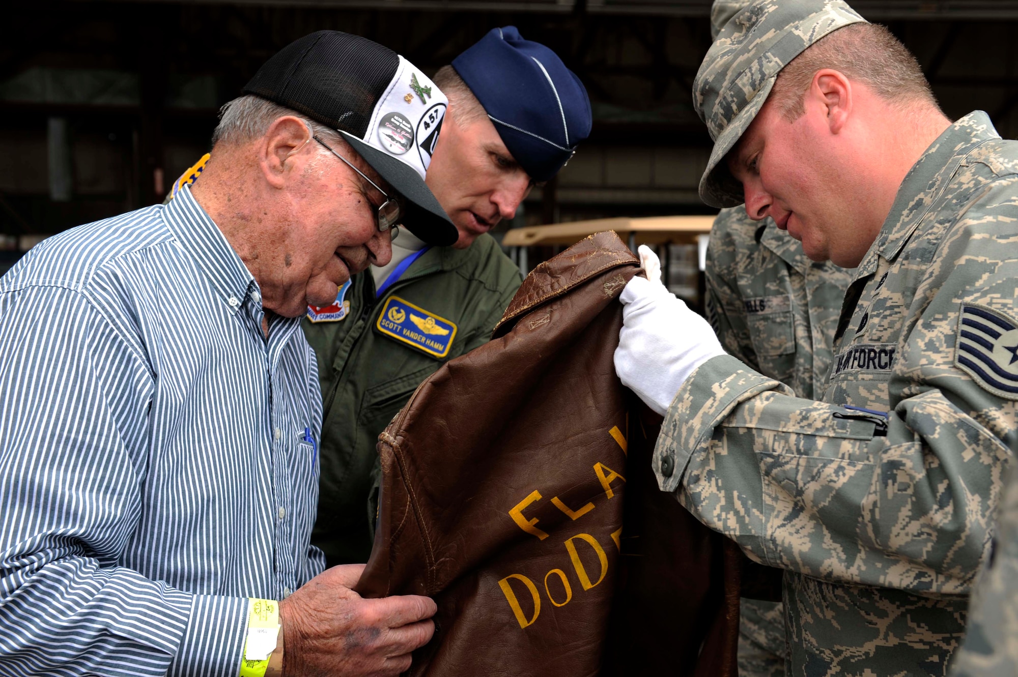 (Right to Left) Tech. Sgt. Steven Wilson, 28th Bomb Wing Public Affairs NCO in charge, and Col. Scott Vander Hamm, 28th Bomb Wing commander, and Clayton Bejot, B-17 Flying Fortress pilot from World War ll, survey his "Flak Dodger" jacket during the Dakota Thunder open house and air show here, May 30. Sergeant Wilson, who is also the South Dakota Air and Space Museum director, began searching for Mr. Bejot's whereabouts after finding a picture of the pilot in a book written about this particular B-17. The jacket still contains the artwork depicting all of Mr. Bejot's missions over Europe and the words "Flak Dodger" written on the back. (U.S. Air Force photo by Airman 1st Class Corey Hook)