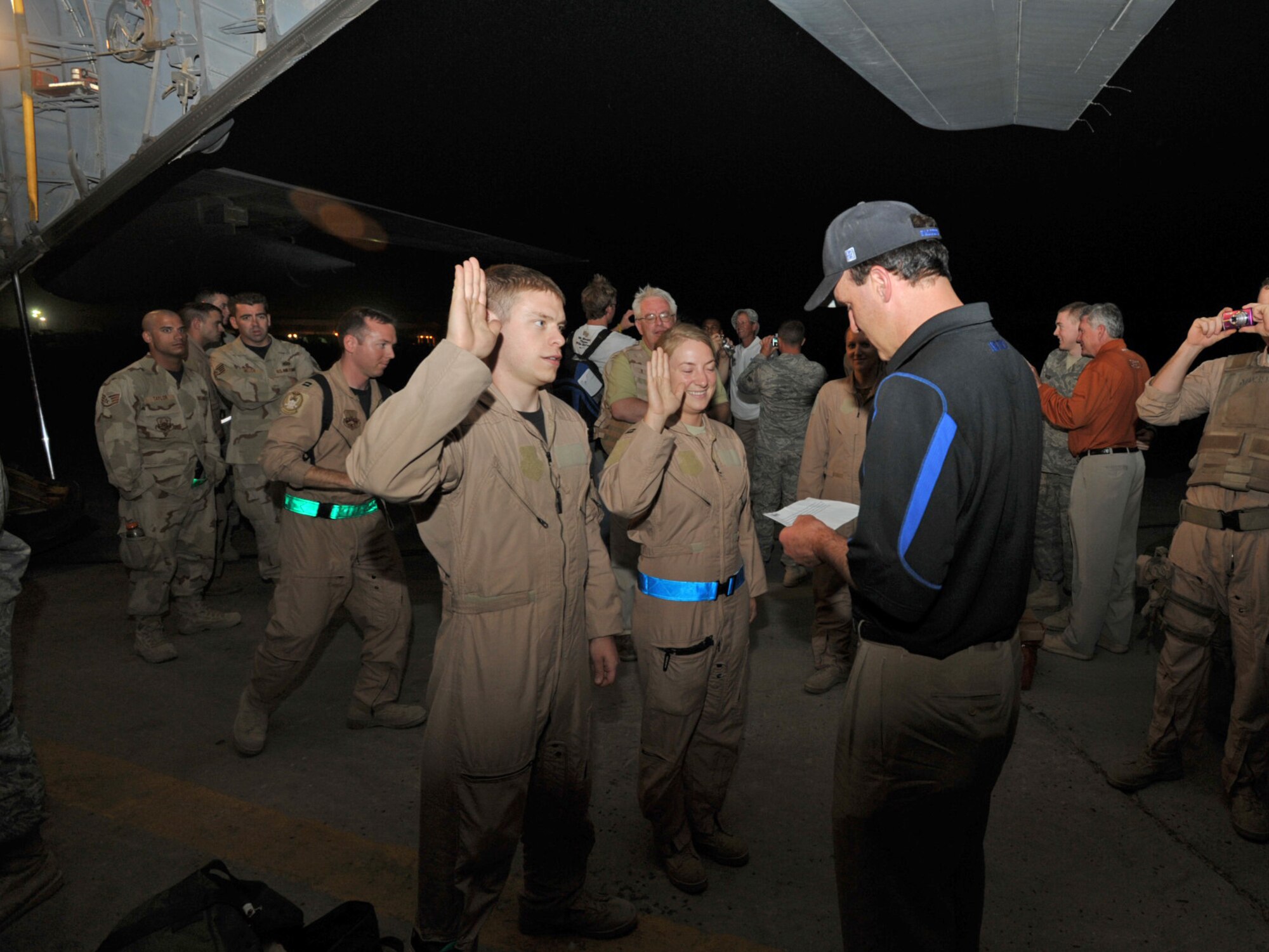 Troy Calhoun, head football coach at the Air Force Academy, promotes Phil Shapiro and Alecia Fogerty to the rank of Captain during a late-night impromptu ceremony on a flightline in Iraq. Both officers are Air Force C-130 Hercule pilots who flew Calhoun and six other NCAA football coaches to visit troops in Bagdad, Iraq, on June 1. The visit was part of Coaches Tour 2009, a second annual morale-boosting mission organized by Morale Entertainment, LLC., in association with Armed Forces Entertainment. Calhoun had the authority to promote the captains as a former academy graduate and Air Force officer. Capt. Eric Junkins, a KC-135 pilot assigned to the 931st Air Refueling Group, was part of the crew that flew the coaches from the United States. (U.S. Air Force photo/Tech. Sgt. Jason Schaap)