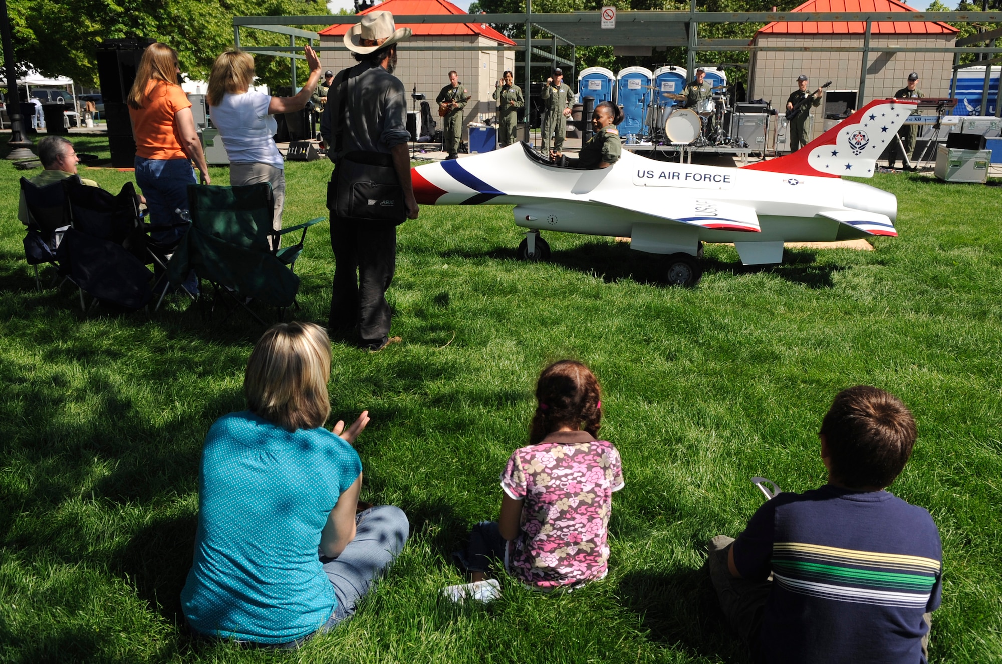 Salt Lake City locals watch Master Sgt. Regina Coonrod "zoom" by them in a toy-model F-16 Fighting Falcon during the "Our Nation's Defenders Showcase" at Pioneer Park for Air Force Week Salt Lake City June 2. Sergeant Coonrod is a vocalist with the band Max Impact, a performance unit with the United States Air Force Band from Bolling Air Force Base, Washington, D.C. (U.S. Air Force photo/Staff Sgt. Desiree N. Palacios)