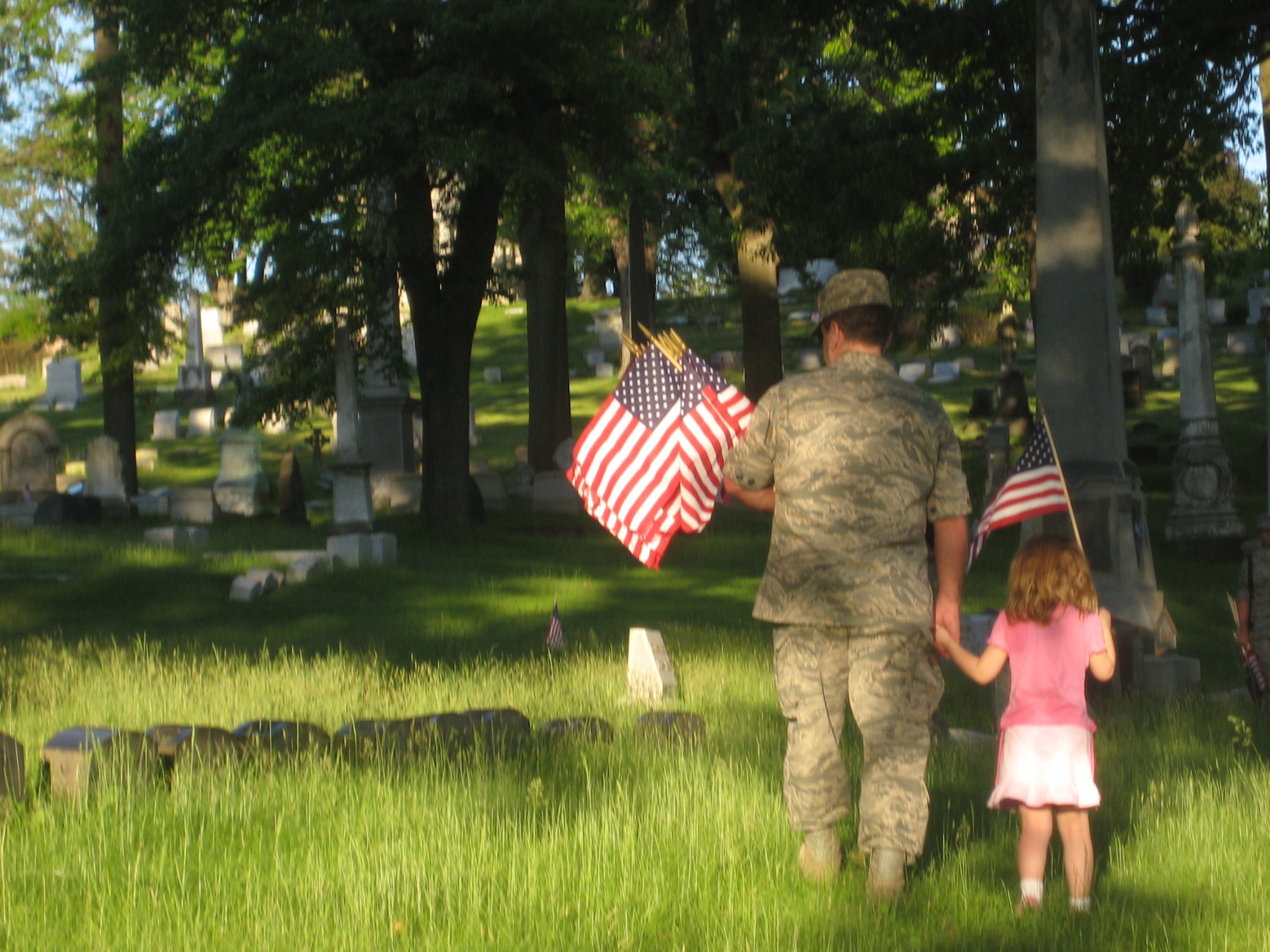 Master Sgt. Anthony W. Cunningham, First Sergeant, 32nd Aerial Port Squadron, and daughter, Shannon, display U.S. flags on service members' gravesites at Allegheny Cemetery, May 21, in preparation of the Memorial Day observance. (photo by Staff Sgt. Keith R. Schmocker)