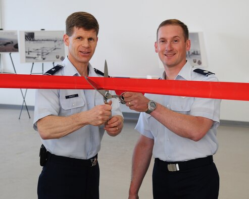 Brig. Gen. Mark W. Graper, 354th Fighter Wing commander, and Lt. Col. Gregory Church, 353rd Combat Training Squadron commander, ceremoniously cut the ribbon to make the opening of the new RED FLAG-Alaska operations and maintenance facility official. The project was a year long, $12 Million conversion of an outdated aircraft maintenance back shop. (U.S. Air Force photo/Airman 1st Class Willard E. Grande II)