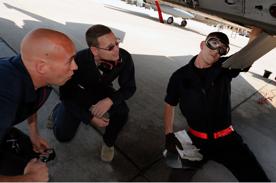 LANGLEY AIR FORCE BASE, Va. -- Staff Sgt. Tim Knighting, 71st Aircraft Maintenance Unit F-15 crew chief, looks into the bottom of an F-15C alongside 1st Fighter Wing Command Chief Master Sgt. Kevin Slater,  while Airman Mike Poudrier, 71st Aircraft Maintenance Unit F-15 crew chief, performs a post flight inspection.  Chief Slater spent the afternoon with maintainers from the 71st Aircraft Maintenance Unit here June 1.  (U.S. Air Force photo/Senior Airman Vernon  Young)