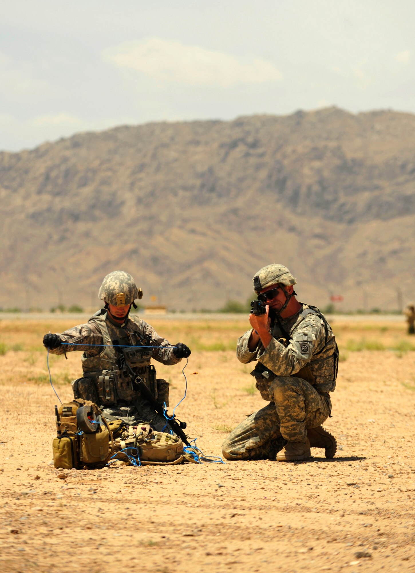 Staff Sgt. Scott Saenz prepares a drag line while being covered by Army Sgt. Mike Ridgeway during joint improvised explosive device training May 5 at Kandahar Airfield, Afghanistan. Sergeant Saenz is an explosive ordnance disposal technician with the 755th Explosive Ordnance Disposal unit, and Sergeant Ridgeway is an infantryman from the 82nd Airborne. (U.S. Air Force photo/Staff Sgt. James L. Harper Jr.) 
