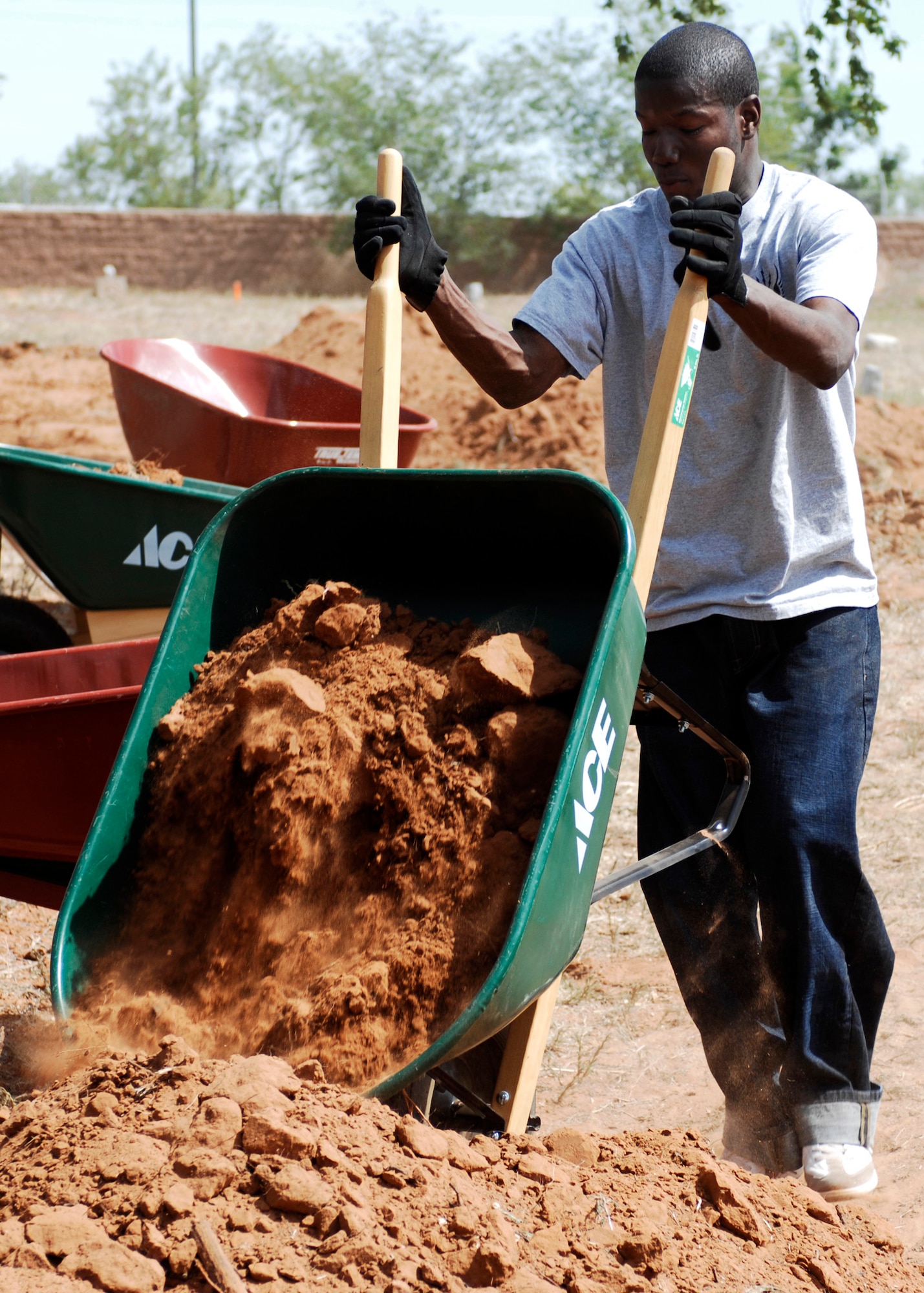 CANNON AIR FORCE BASE, N.M. -- Senior Airman Ronald Brooks, 27th Special Operations Logistics Readiness Squadron, empties a wheelbarrow during a restoration project at the Blacktower Cemetery. Base Airmen dug for two days, May 29-30, in the hopes of uncovering headstones or more from the abandoned cemetery adjacent to the Chavez Manor housing area. (U.S. Air Force photo by Greg Allen) 