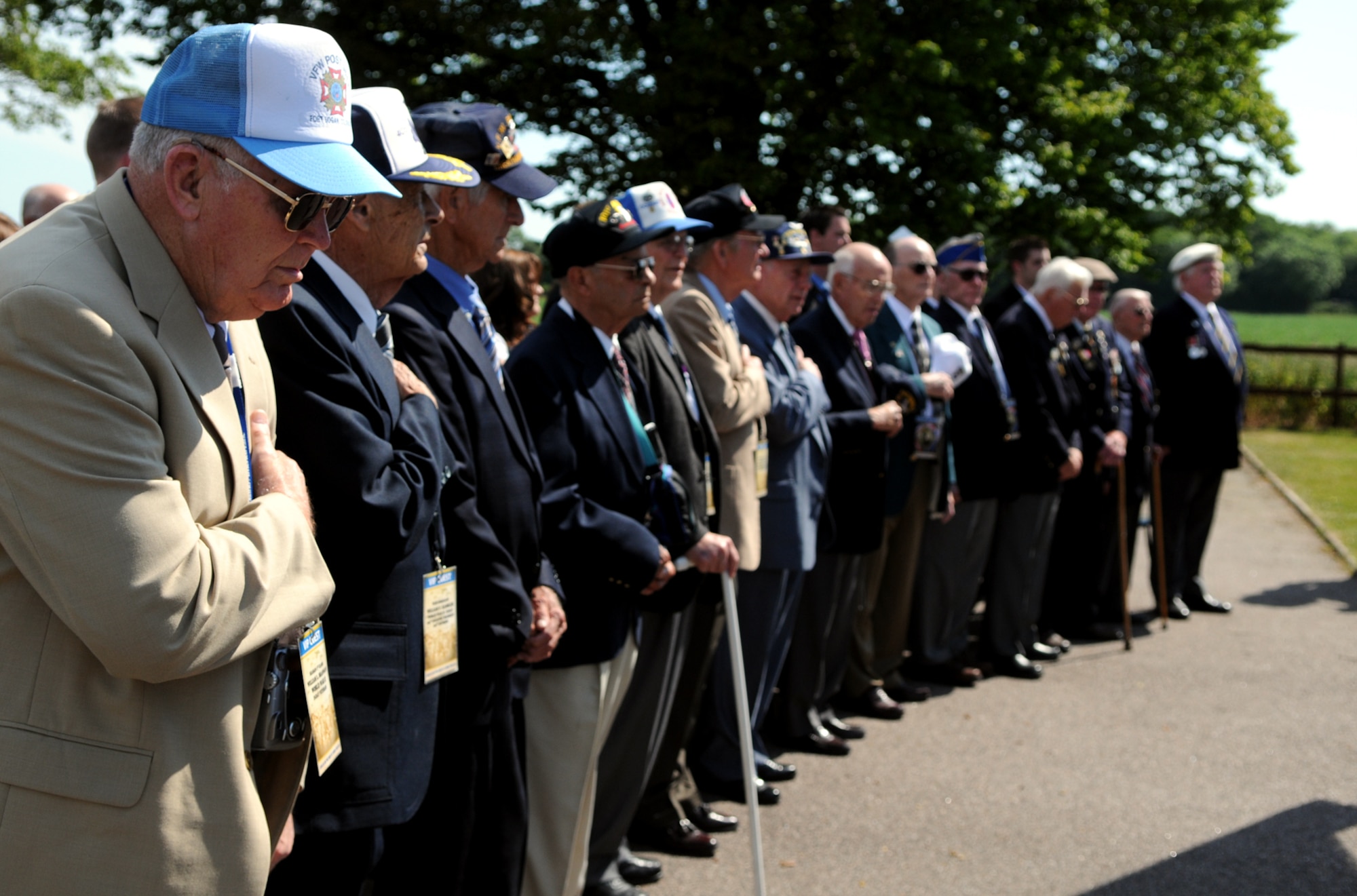 American and British World War II veterans on a tour of significant sites in the European Theater render honors during the singing of the Star Spangled Banner at Thorpe Abbots June 1.  A small ceremony at the airfield included eyewitness accounts of the D-Day invasion, some given by the veterans themselves and some read from interview notes by college students, and the laying of a memorial wreath at the site.   (U.S. Air Force photo by Staff Sgt. Austin M. May)