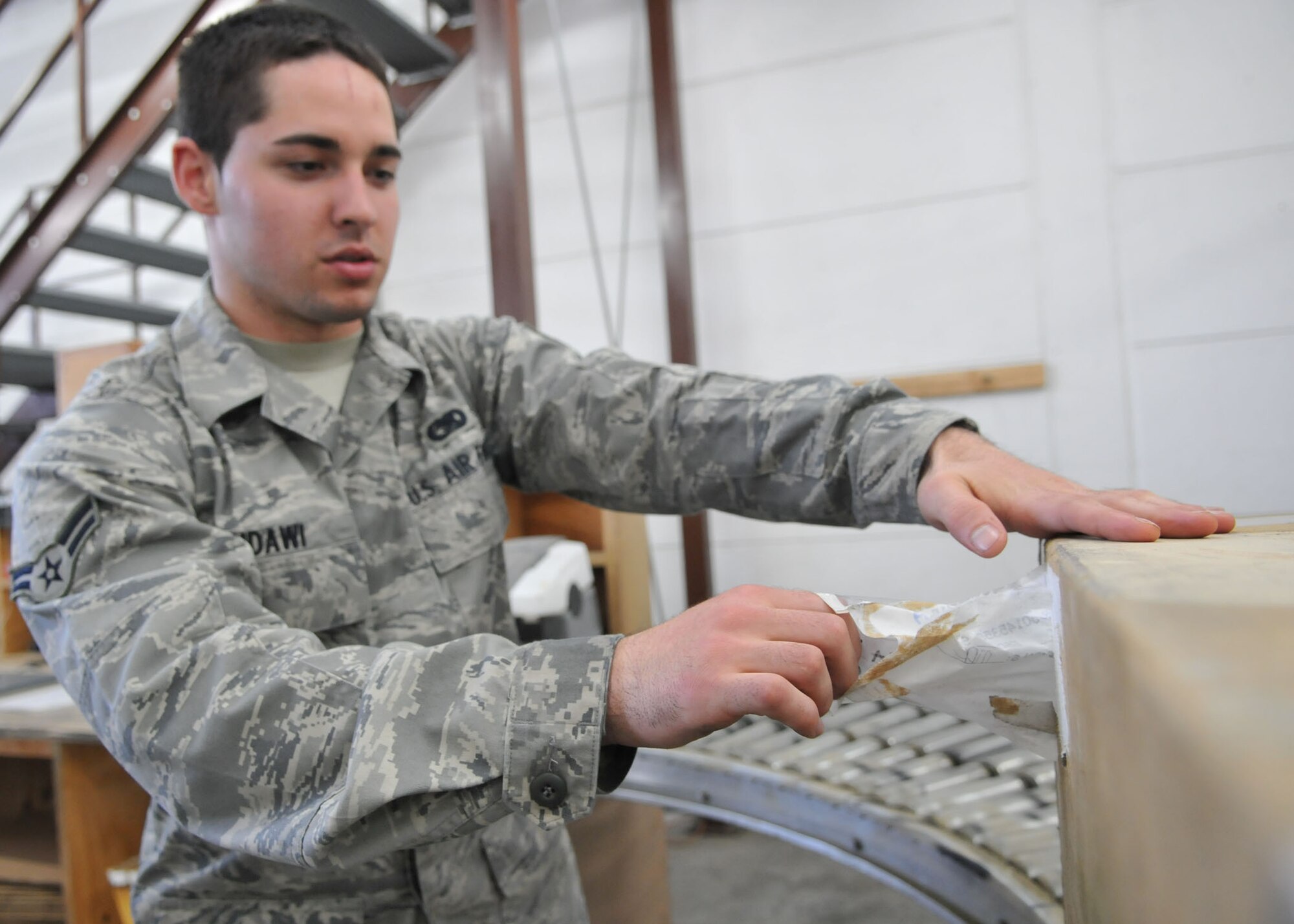 SPANGDAHLEM AIR BASE, Germany – Airman 1st Class Ryan Sidawi, 52nd Logistics Readiness Squadron travel management office, removes a label from a package. TMO prepares general cargo for out-processing and shipment. (U.S. Air Force photo by Airman 1st Class Nick Wilson)