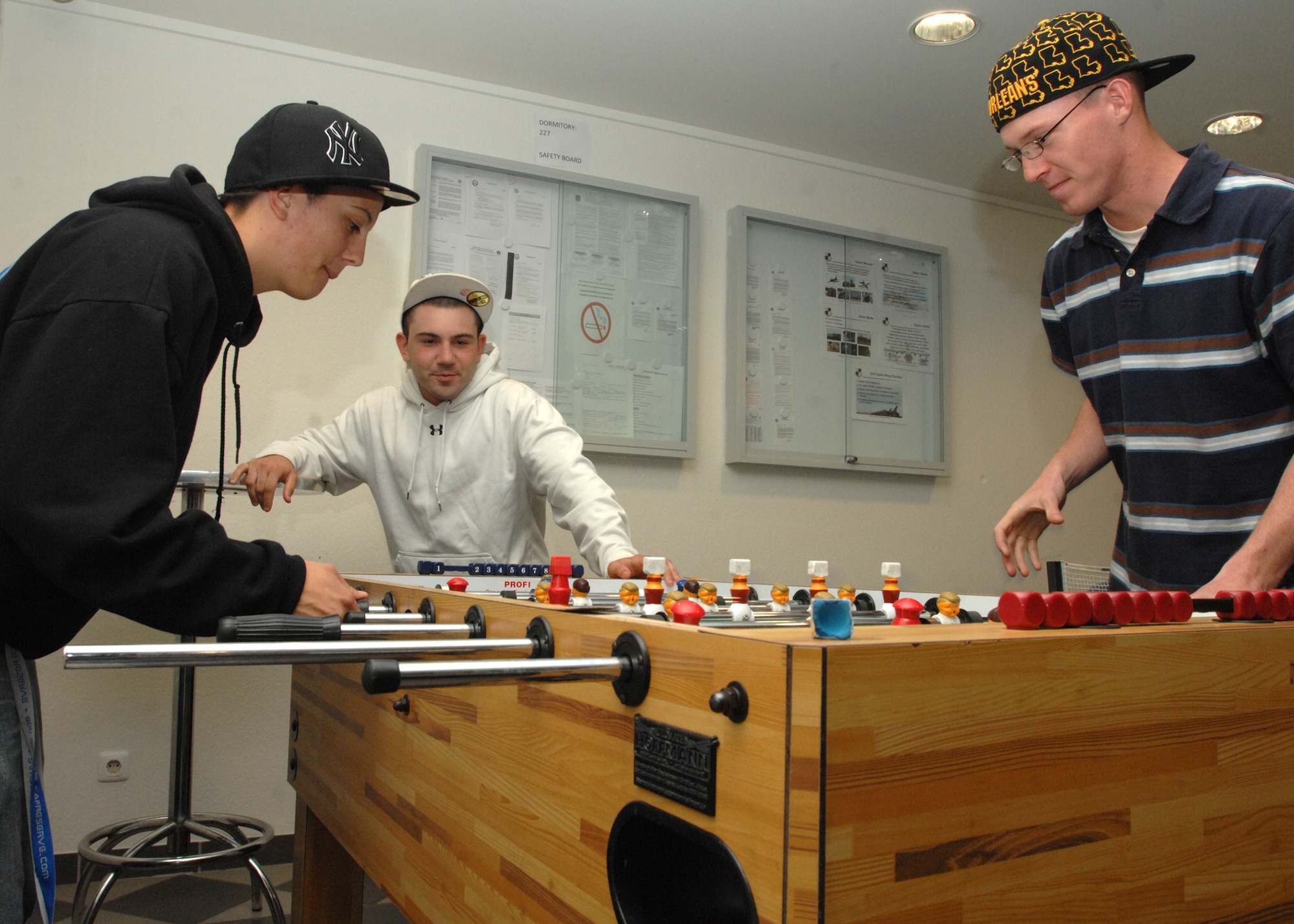 SPANGDAHLEM AIR BASE, Germany -- Airman Charla Maddox and Airman 1st Class Jeremy Johnston, play foosball as Airman 1st Class Christopher Perez, all 52nd Security Forces Squadron, looks on in a dormitory here May 27, 2009.  The Airmen utilize the day rooms that feature ping pong, foosball and billiards. (U.S. Air Force photo by Senior Airman Jenifer H. Calhoun)