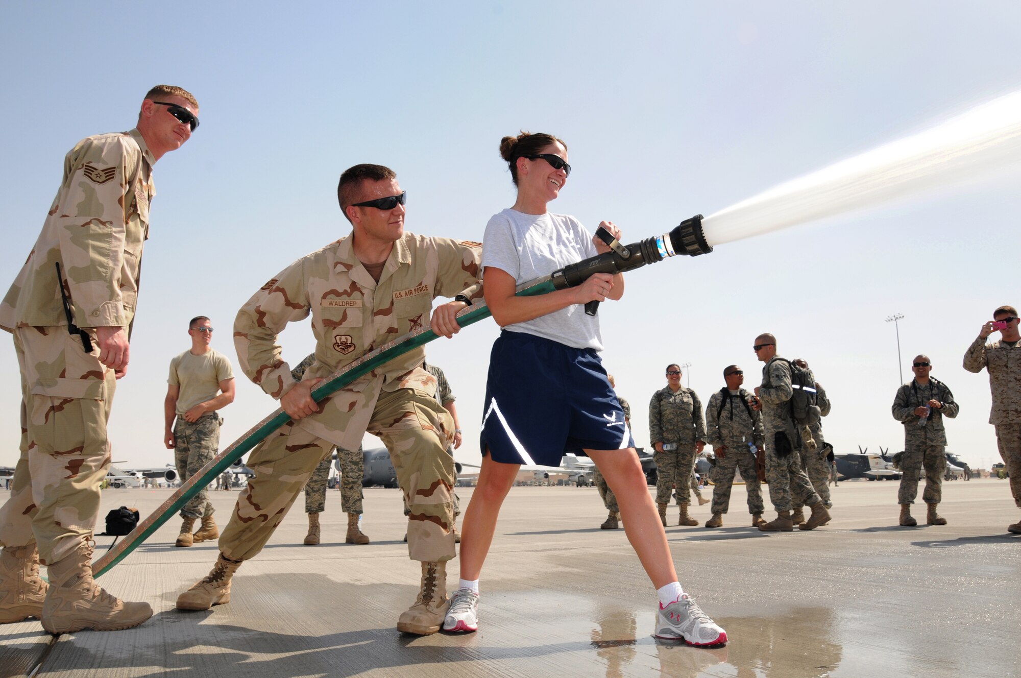 Staff Sgt. Patrick Ogborn looks on as Staff Sgt. Waldrep supports Senior Airman Mariah Pomoty as she tries her hand at using a fire hose at Flightline Fest, May 29, 2009, in an undisclosed location in Southwest Asia.  The 379th Air Expeditionary Wing hosted the half day event which gave base personnel the chance to look at static aircraft displays and other equipment up close, all without interrupting the mission of providing combat airpower throughout the U.S. Central Command's area of responsibility.  Sergeants Ogborn and Waldrep are both firefighters with the 379th Expeditionary Civil Engineer Squadron.  Sergeant Ogborn is from Phoenix, Ariz. and is deployed from Dover Air Force Base, Del.  Sergeant Waldrep is from Lynchberg, Va. and is deployed from Eglin Air Force Base, Fla.  Airman Pomoty, a medic with the 379th Expeditionary Medical Group is from Reno, Nev. and is deployed from the Reno Air National Guard base.  All are deployed in support of Operations Iraqi and Enduring Freedom and Combined Joint Task Force-Horn of Africa. (U.S. Air Force photo by Senior Master Sgt. Brad Fallin/released)