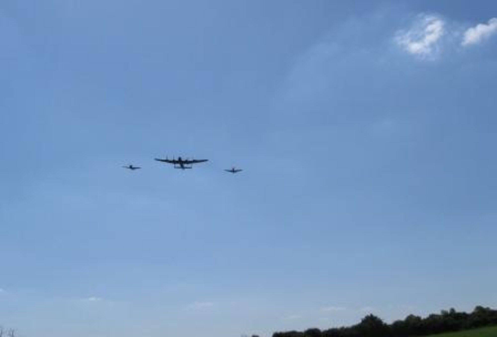 A Hawker Hurricane, Avro Lancaster and  Supermarine Spitfire perform a memorial flyover at a memorial dedication service at St. Mary's Church in Yelden, Bedfordshire. 