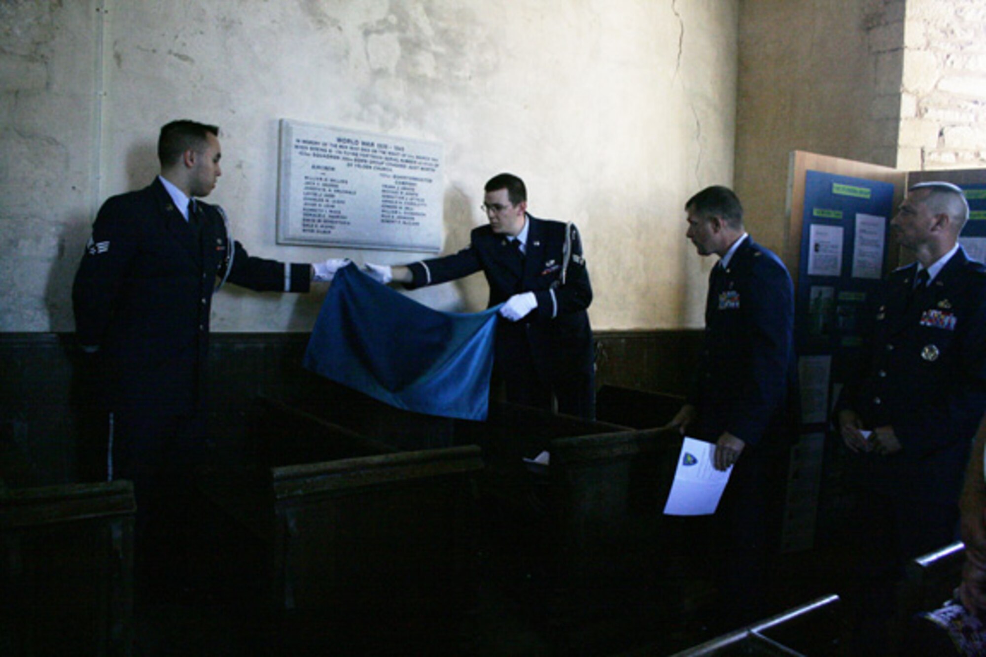 Chaplain (Lt. Col.) Walter Bean unveils a memorial plaque at a dedication service at St. Mary's Church, Yelden, Bedfordshire. The service honored U.S. military personnel who died March 24, 1944 when a B-17 Flying Fortress crashed upon takeoff from RAF Cheveston. The crash killed 11 aircrew members, eight military personnel on the ground and two children from the village. 