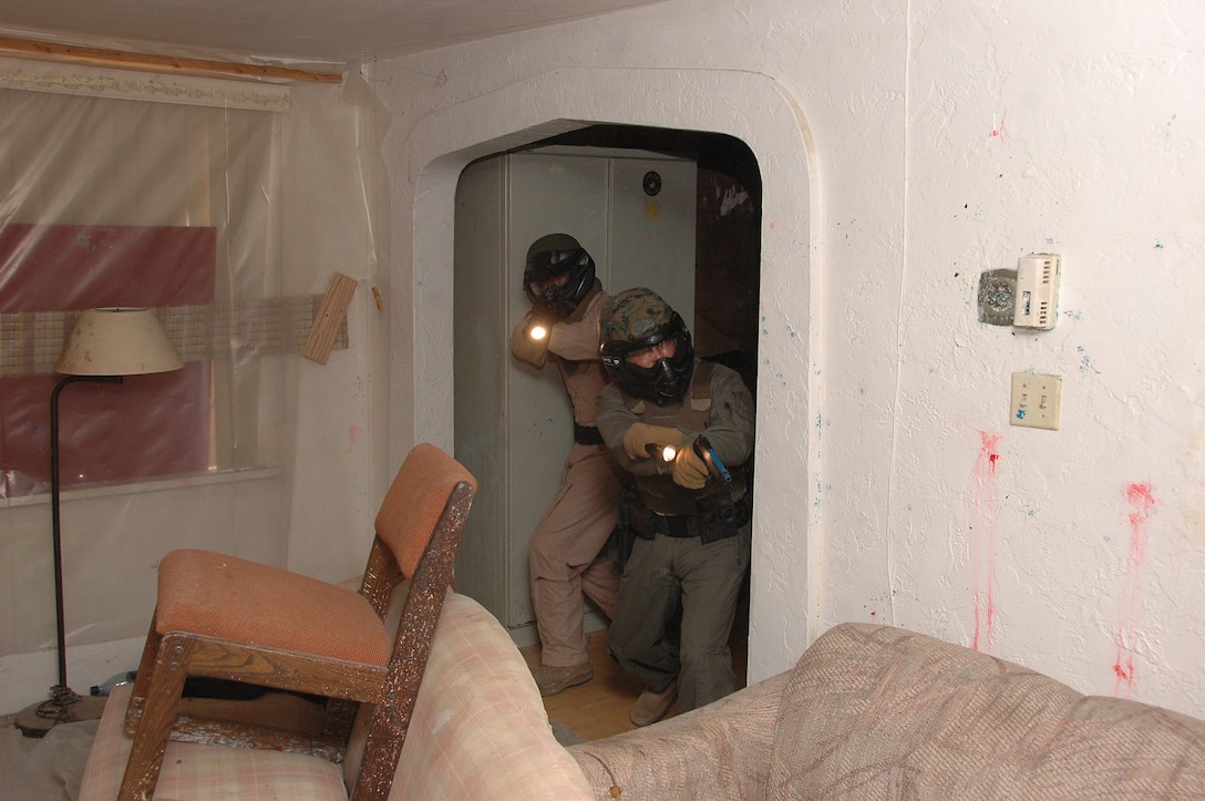 Lance Cpl. Michael Hargrove, left, and Lance Cpl. Brian Ambelis, security augments, clear a room as they make their way to a hostage during a hostage simulation in a training house June 2, 2009, at the Marine Corps Air Station in Yuma, Ariz. The exercise, which included the use of nonlethal live ammunition, was designed to improve the officers' tactics and confidence in shootouts.
