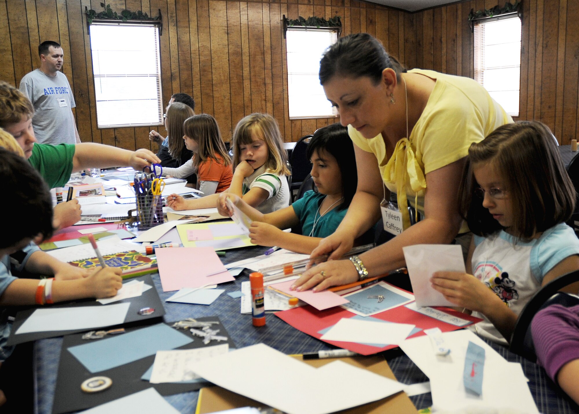 CANNON AIR FORCE BASE, N.M. -- Tyleen Caffrey, 27th Special Operations Medical Group, helps children scrapbook in Ruidoso, N.M., May 16. Mrs. Caffrey volunteered her assistance at the first Air Commando Family Retreat, offered by the base chapel. The retreat?s objective was to assist families during pre- and post-deployment periods. (U.S Air Force photo by Airman 1st Class Evelyn Chavez)