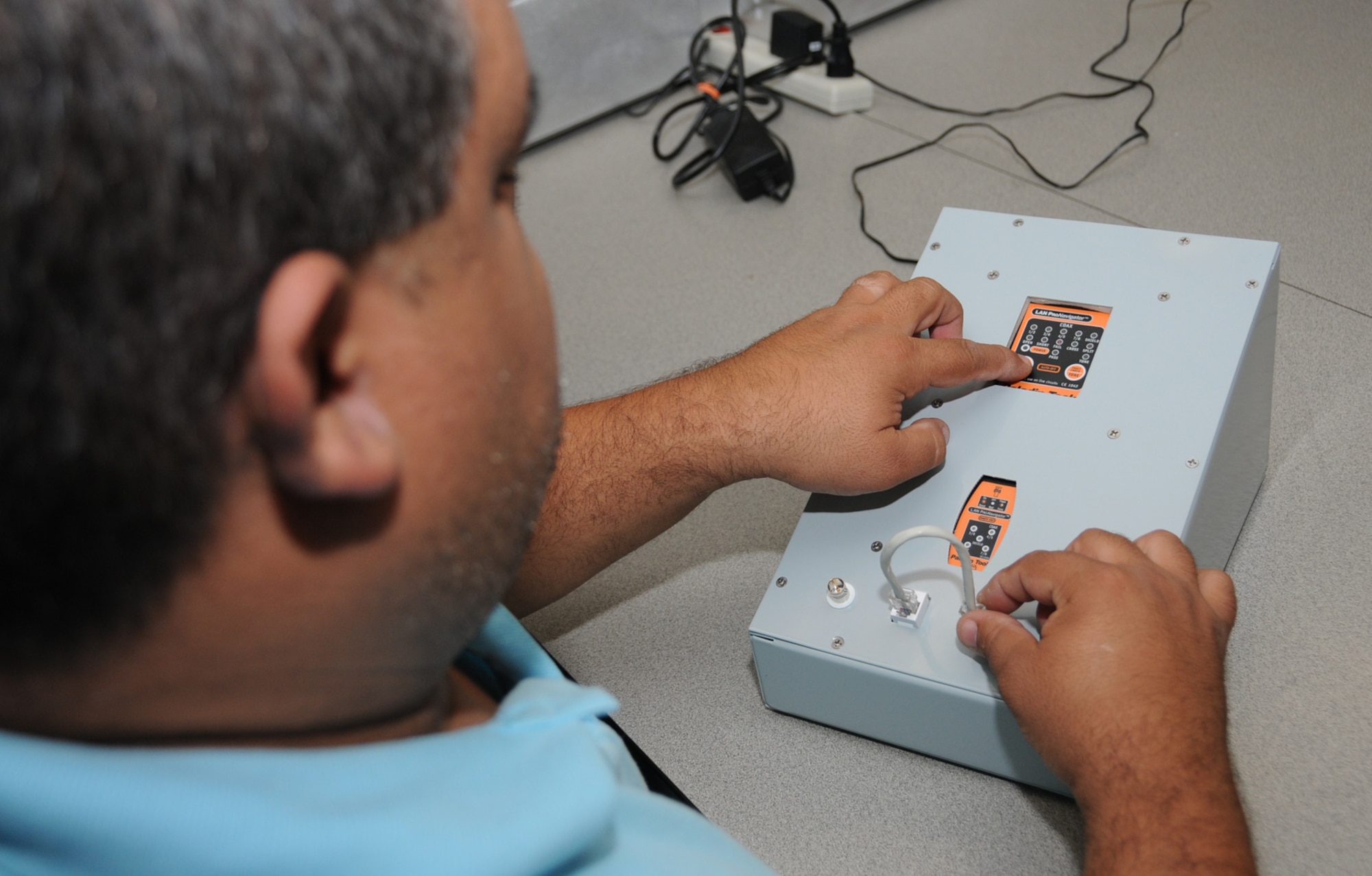 Juan Cobar, an electronic principles instructor in the 332nd TRS, tests a cable on the network cable tester in Dolan Hall May 28.  (U.S. Air Force photo by Kemberly Groue)