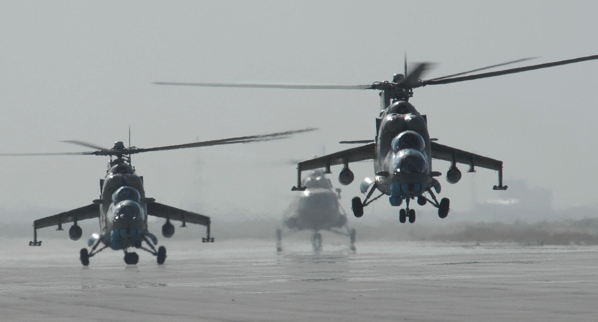 Two MI-35 attack helicopters from the Afghan National Army Air Corps launch from the airport in Kabul, Afghanistan, on a gunnery training mission May 27 as another ANAAC MI-17 transport lands in the background.  This mission was the first time rockets have been flown by the Afghan air corps in more than eight years and will eventually allow the Afghans to provide their own close-air support. (U.S Air Force photo/Tech. Sgt. Parker Gyokeres)