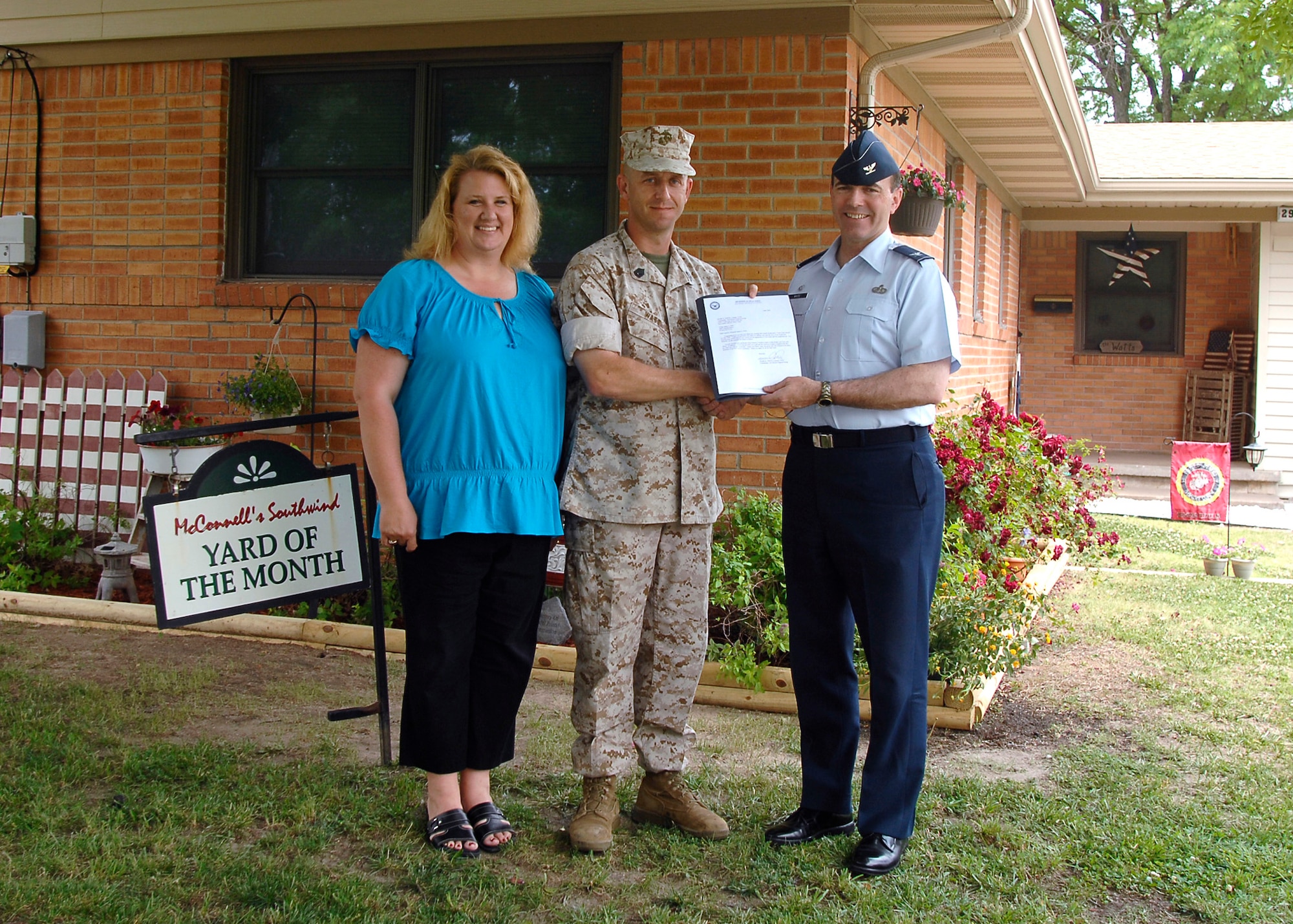 MCCONNELL AIR FORCE BASE, Kan. -- Colonel Mark White, 22nd Mission Support Group commander, recognizes Gunnery Sgt. James Watt, with the Instructor and Inspection Staff for Wichita, Kan., along with wife Erika for winning the yard of the month, June 1. The Watt family won the yard of the month for June. (Photo by Senior Airman Anthony Mejia)