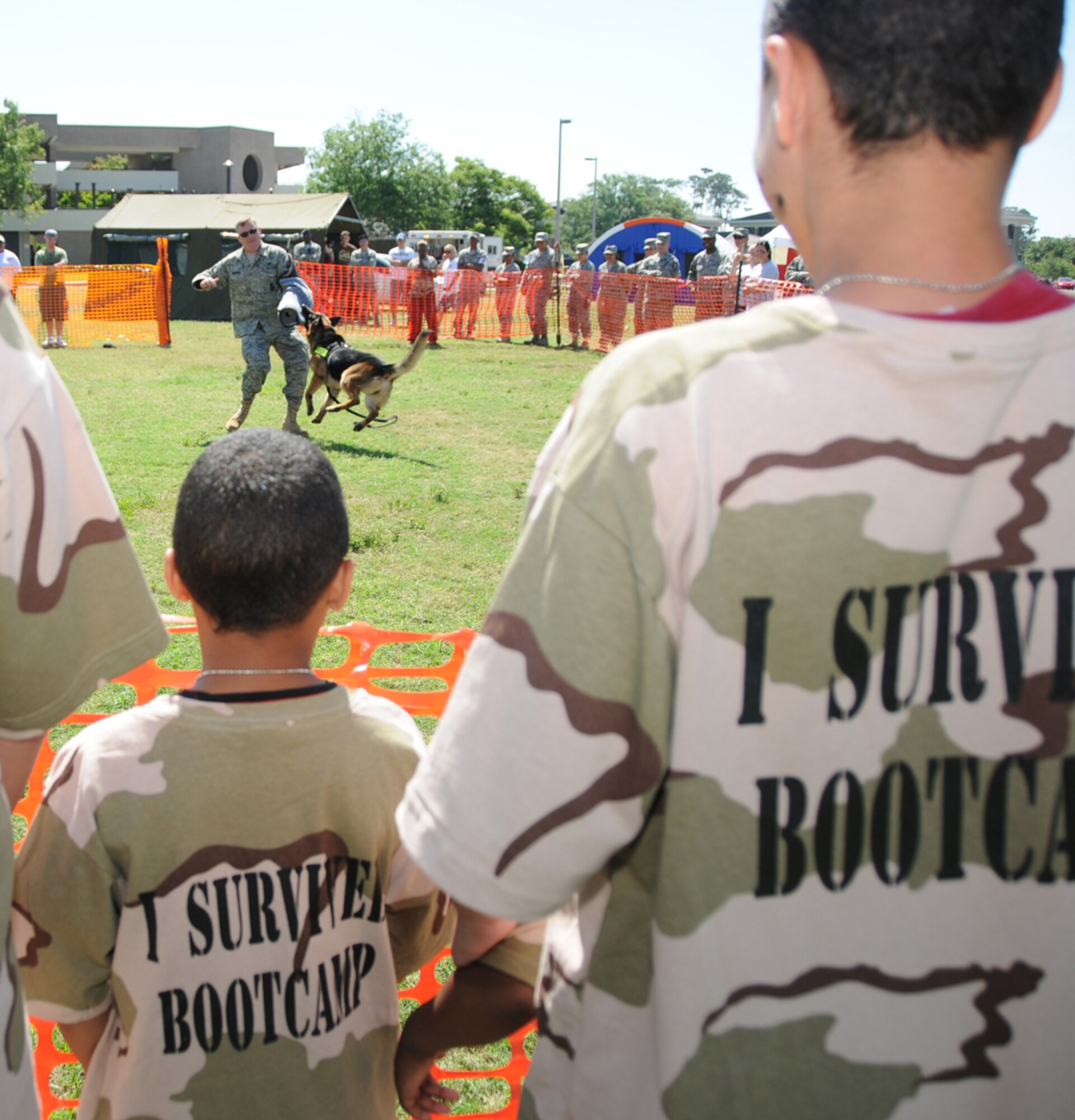 Stephen English, 7, left, and his brother Joshua, 14, watch as Tech. Sgt. Michael Pedersen, 81st Security Forces Squadron, portrays a ‘bad guy’ to demonstrate the capabilities of Gino, his military working dog, and other canine cops in deployed situations. The boys are wearing T-shirts given to Operation Hero participants.  Their parents are Tech. Sgt. Michael and Elldwinia English, 85th Engineering Installation Squadron.  (U.S. Air Force photo by Kemberly Groue)