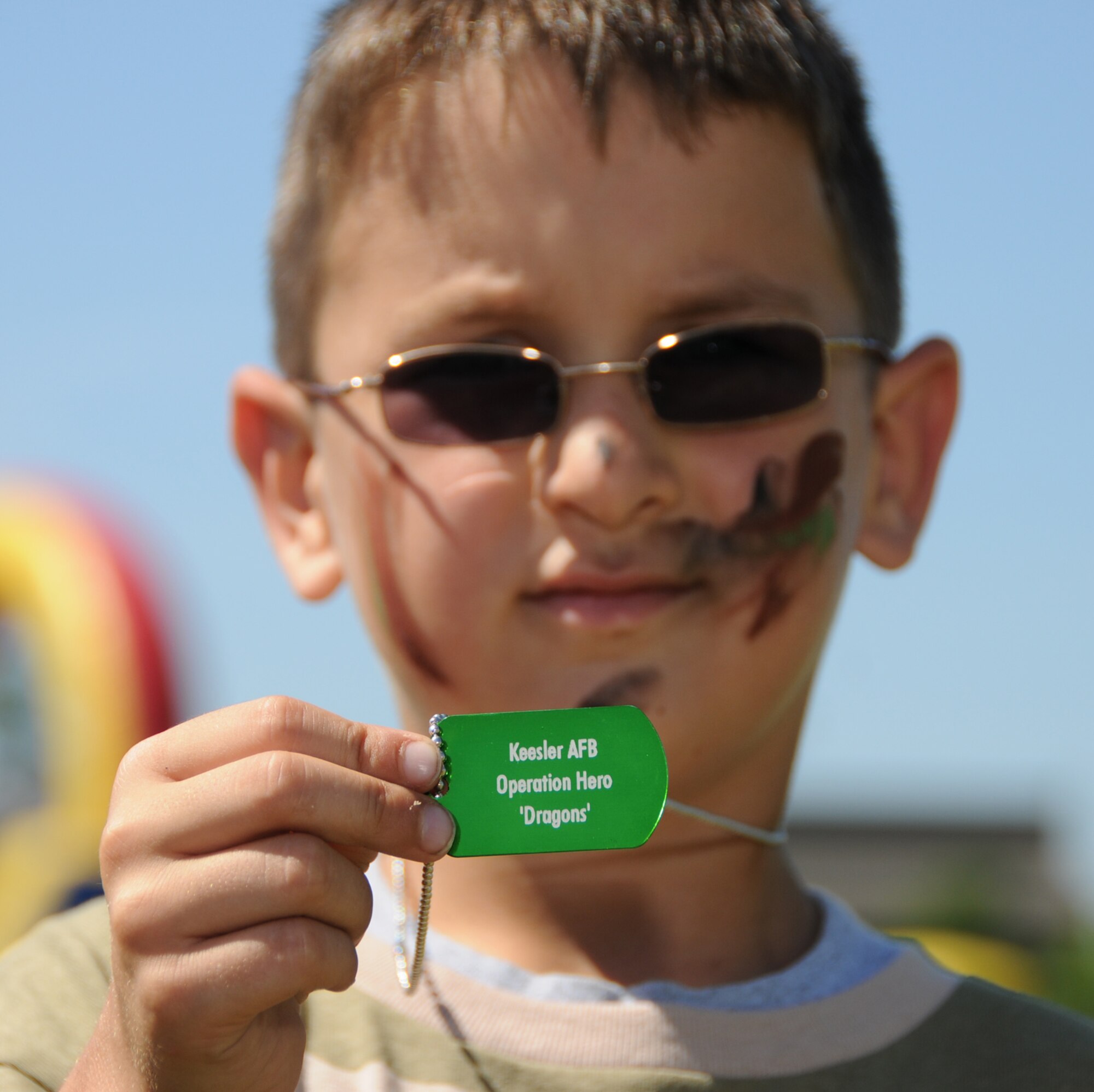 Seven-year-old Carter Hickam, son of Capt. Michael and Michele Hickam, 335th Training Squadron, shows off his dog tag at Saturday’s Operation Hero. The program introduces children to the deployment process.  (U.S. Air Force photo by Kemberly Groue)