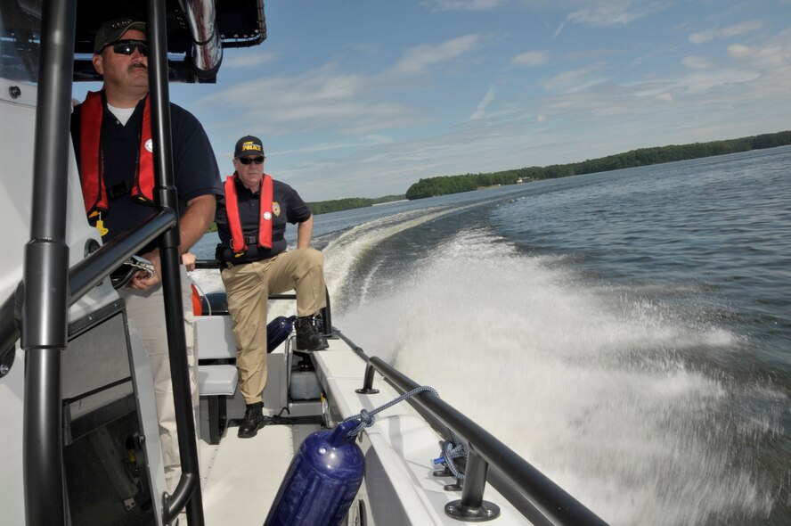 (Left to right) Arnold Engineering Development Center (AEDC) Security Officer Buck Young look on while fellow officers Tommy Winton and Larry Swan get a hand from Dana White, a Brunswick Company trainer and sales representative, secure the new patrol boat’s diver’s door, which allows for water-borne rescues and recoveries. AEDC Security Police trained with White on board the center’s new boat on Woods Reservoir before the ceremonial launch. (Photo by Rick Goodfriend)