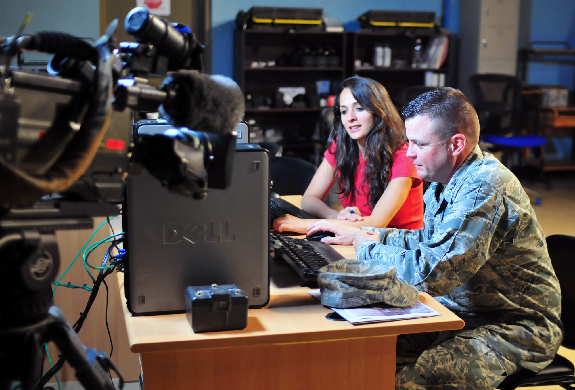 Air Force Capt. William Cooke, deployed from Tyndall Air Force Base in Panama City, Fla., watches NBC Channel 11 Alive news stories leading up to the live Web cast of his sons' graduation along with NBC Baghdad reporter Kianne Sadeq.  In addition to viewing the ceremony online, Cooke's image was transmitted from Al-Faw Palace, Baghdad, back to the Whitewater High School football field in Fayetteville, Ga., so he could be a part of the graduation.  Cooke is serving a six-month tour assigned to Multi-National Forces -- Iraq, Camp Victory. (U.S. Army photo/Master Sgt. Michael Daigle)