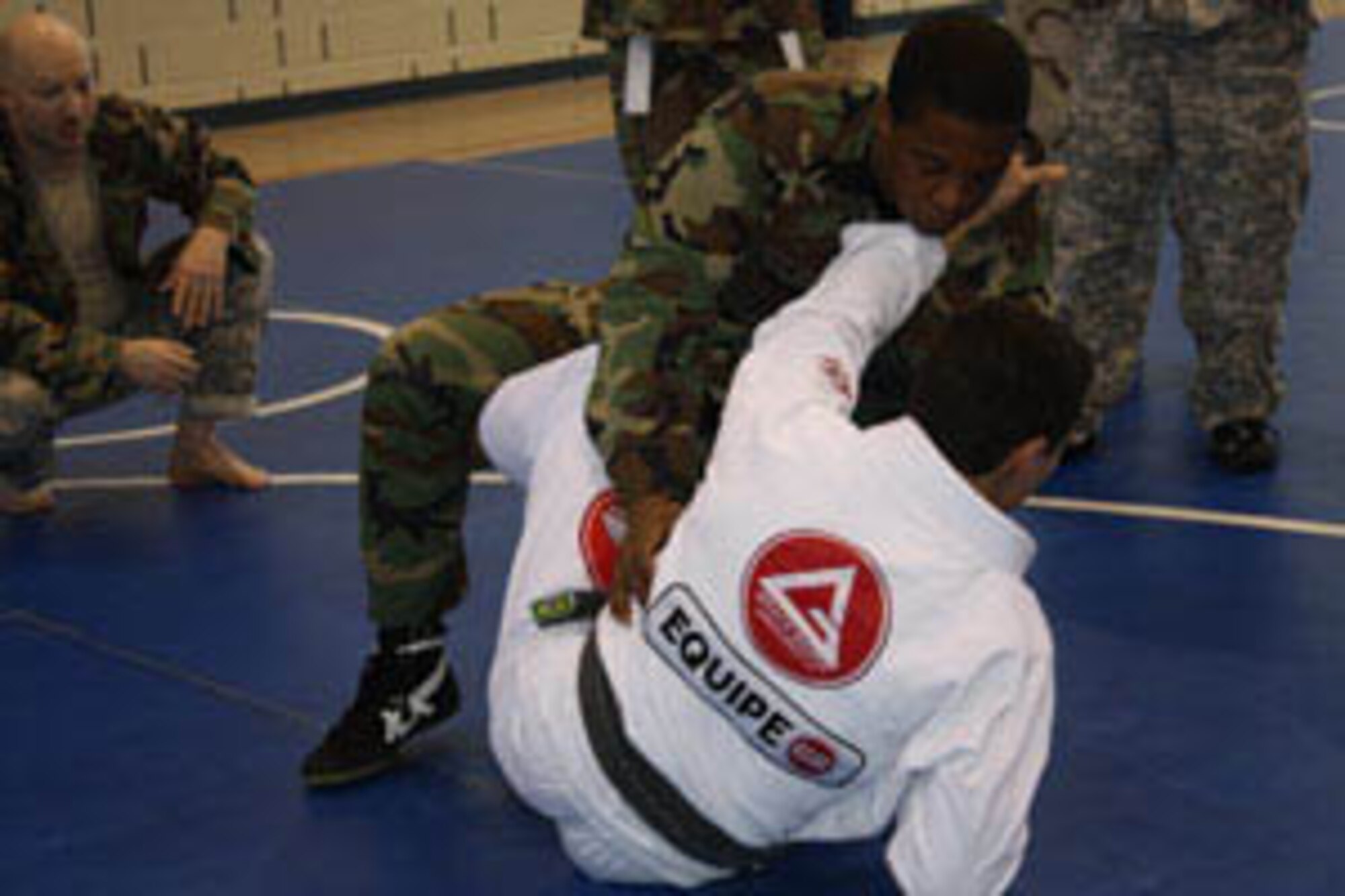 Professor Marcos Barros (in white), a black belt in Gracie Ju Jitsu, teaches combative techniques to SSgt Ruel Taylor of the 110th AOG while Army Spc David Kirby looks on.  Barros was visiting as a guest instructor during classes held at the 129th RTI facilities in Springfield, IL.