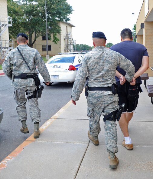 BARKSDALE AIR FORCE BASE, La. -- Senior Airmen Ross Lincoln and Michael Michel, 2d Security Forces Squadron, escort an individual to their patrol car in handcuffs outside the Base Exchange, May 21. Those who are caught shoplifting will be apprehended and reprimanded. (United States Air Force photo by Senior Airman Alexandra Sandoval) (RELEASED)