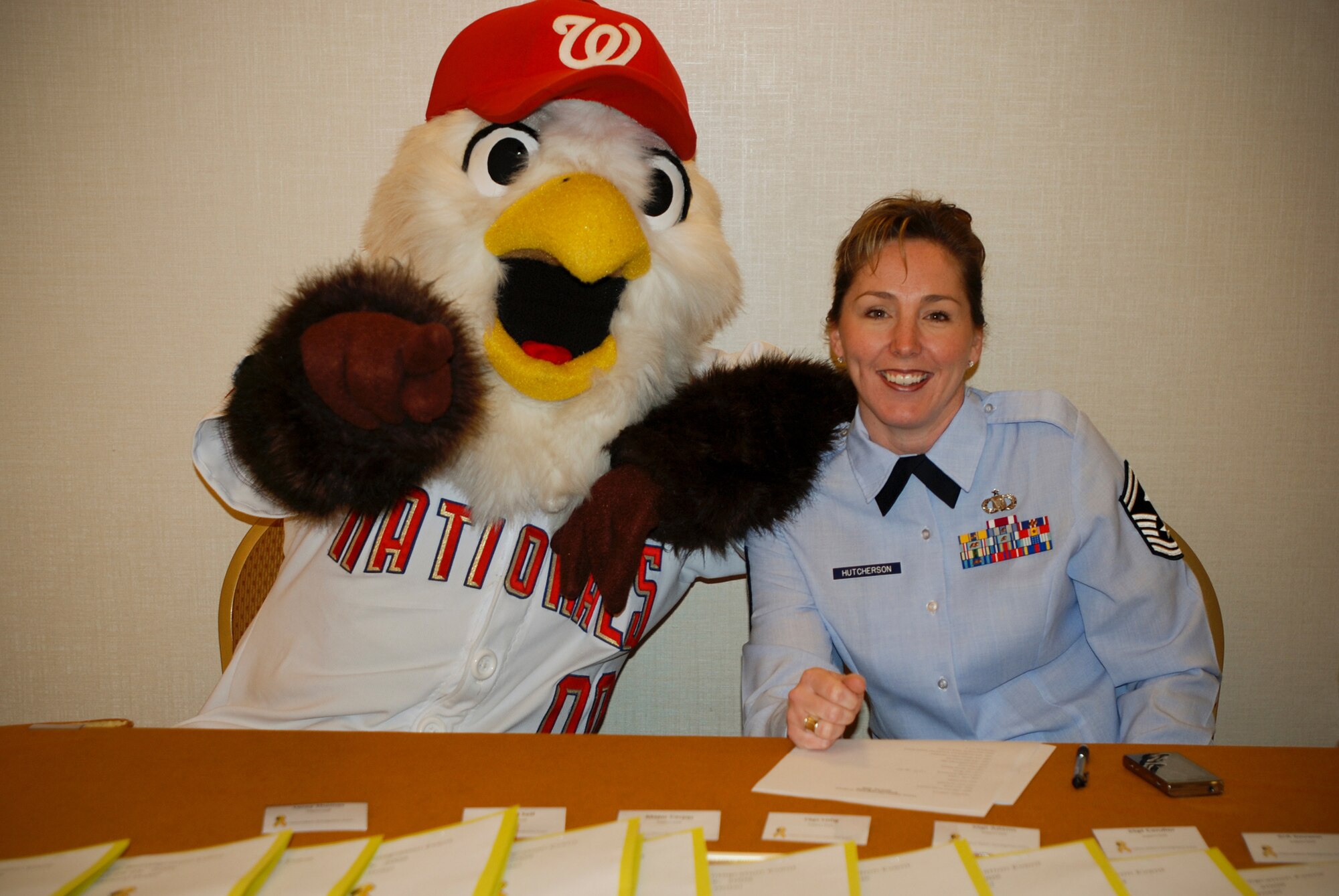 Senior Master Sgt. Jennifer Hutcherson, First Sergant with the 69th Aerial Port Squadron and the 459th Air Refueling Wing yellow ribbon program coordinator welcomes reservists with Screech, the mascot from the Washington Nationals baseballl team at the registration table at the 459th ARW Yellow Ribbon welcome home event.