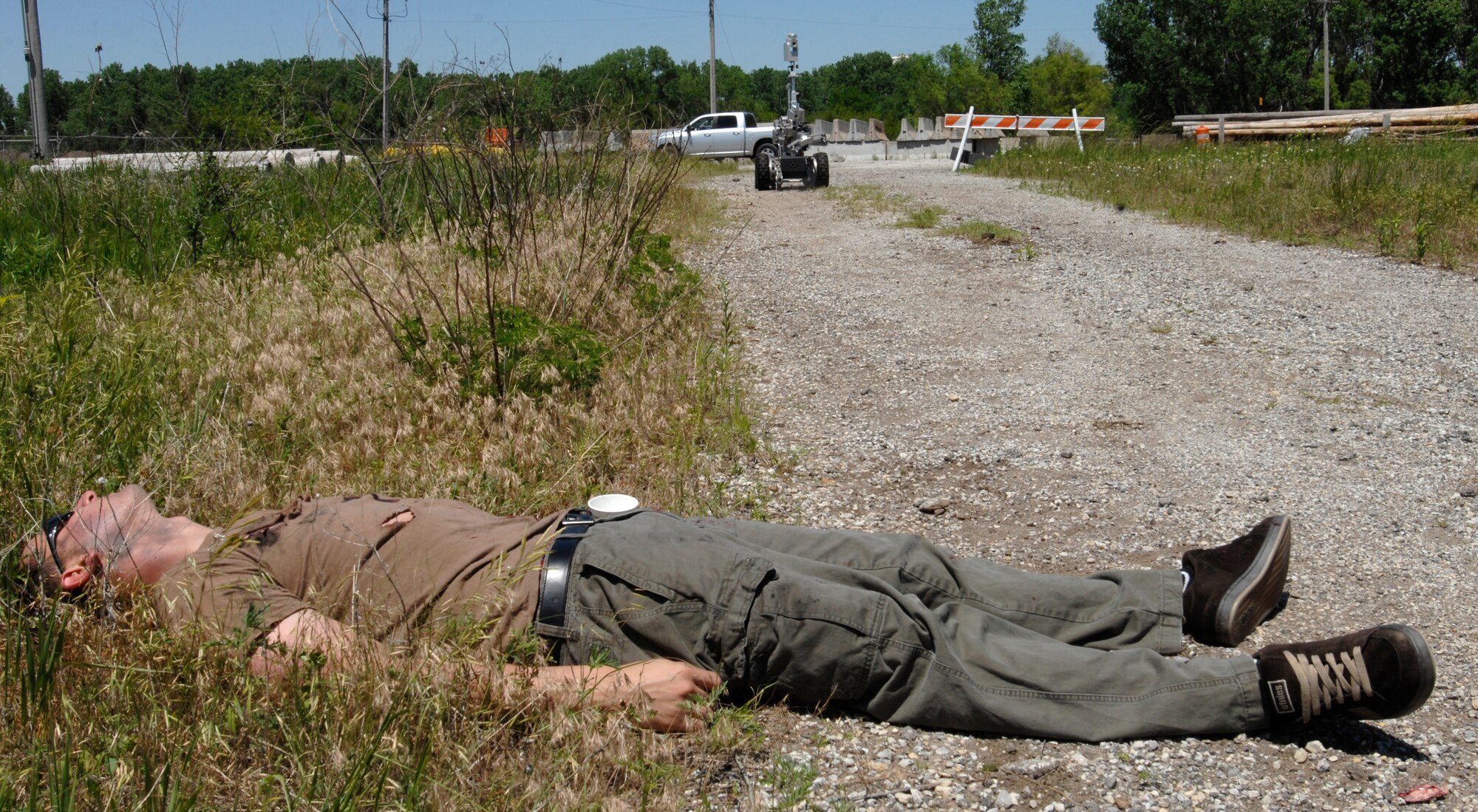 MCCONNELL AIR FORCE BASE, Kan. -- Staff Sgt. James Gumbs, 22nd Operations Group, acts as a casualty as a Explosive Ordnance Disposal robot, roams a path on the obstacle course toward a simulated vehicle explosion during an All Hazards Response training exercise, May 28. The robot’s purpose in this exercise is to ensure no explosive devices are in the area allowing the hazard material team to arrive safely so they can assess and fix the situation. (Photo by Senior Airman Laura Suttles)