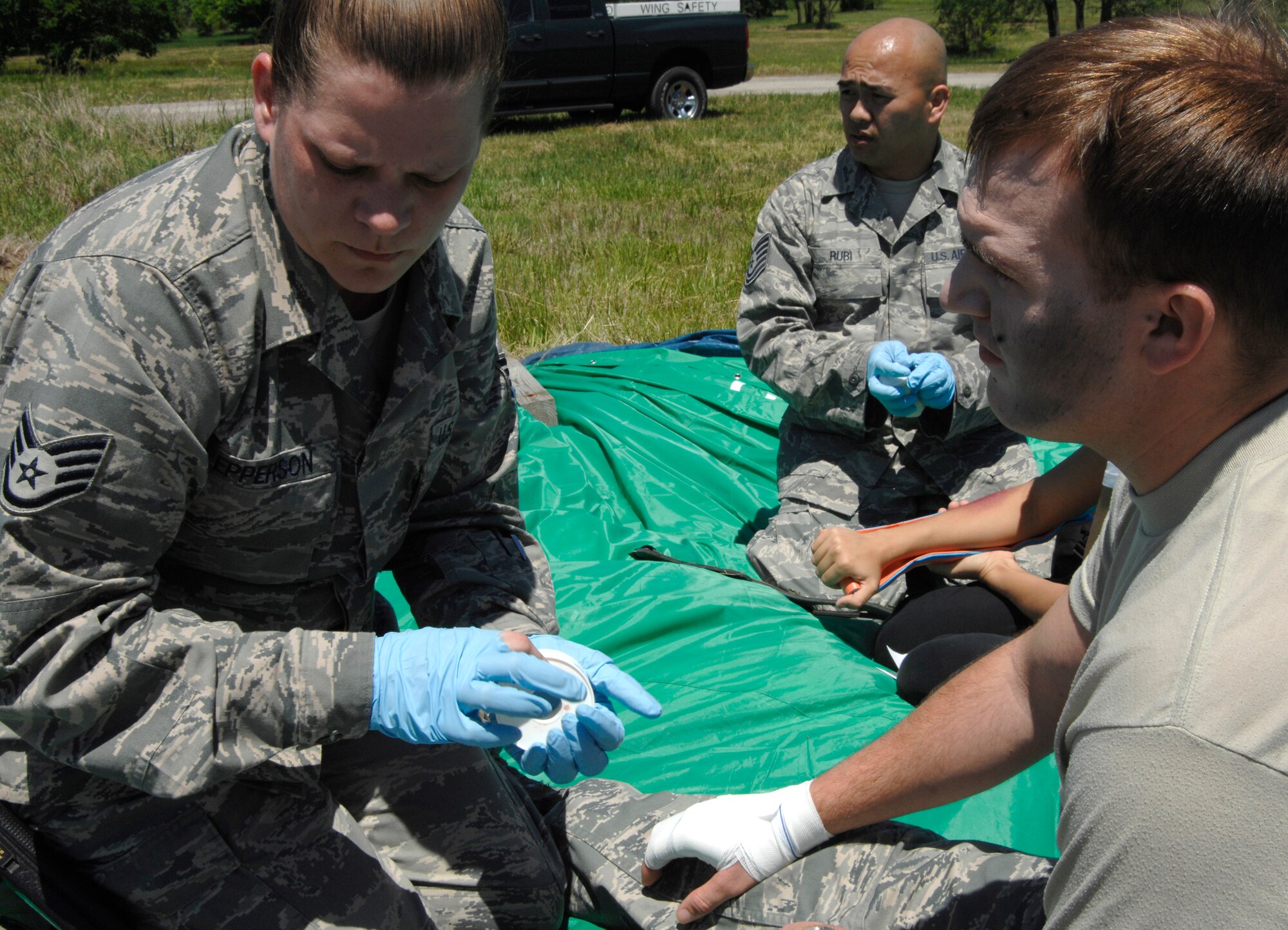 MCCONNELL AIR FORCE BASE, Kan. -- Staff Sgt. Jean Epperson, 22nd Aerospace Medicine Squadron, treats Airman 1st Class Jesse Oliver, 22nd Aircraft Maintenance Squadron, for simulated burns during an All Hazards Response training exercise at the base obstacle course, May 28. The 22nd Medical Group dispatched several members from the base clinic to participate in the exercise and react to a situation where an immediate medical attention was needed. (Photo by Senior Airman Laura Suttles)