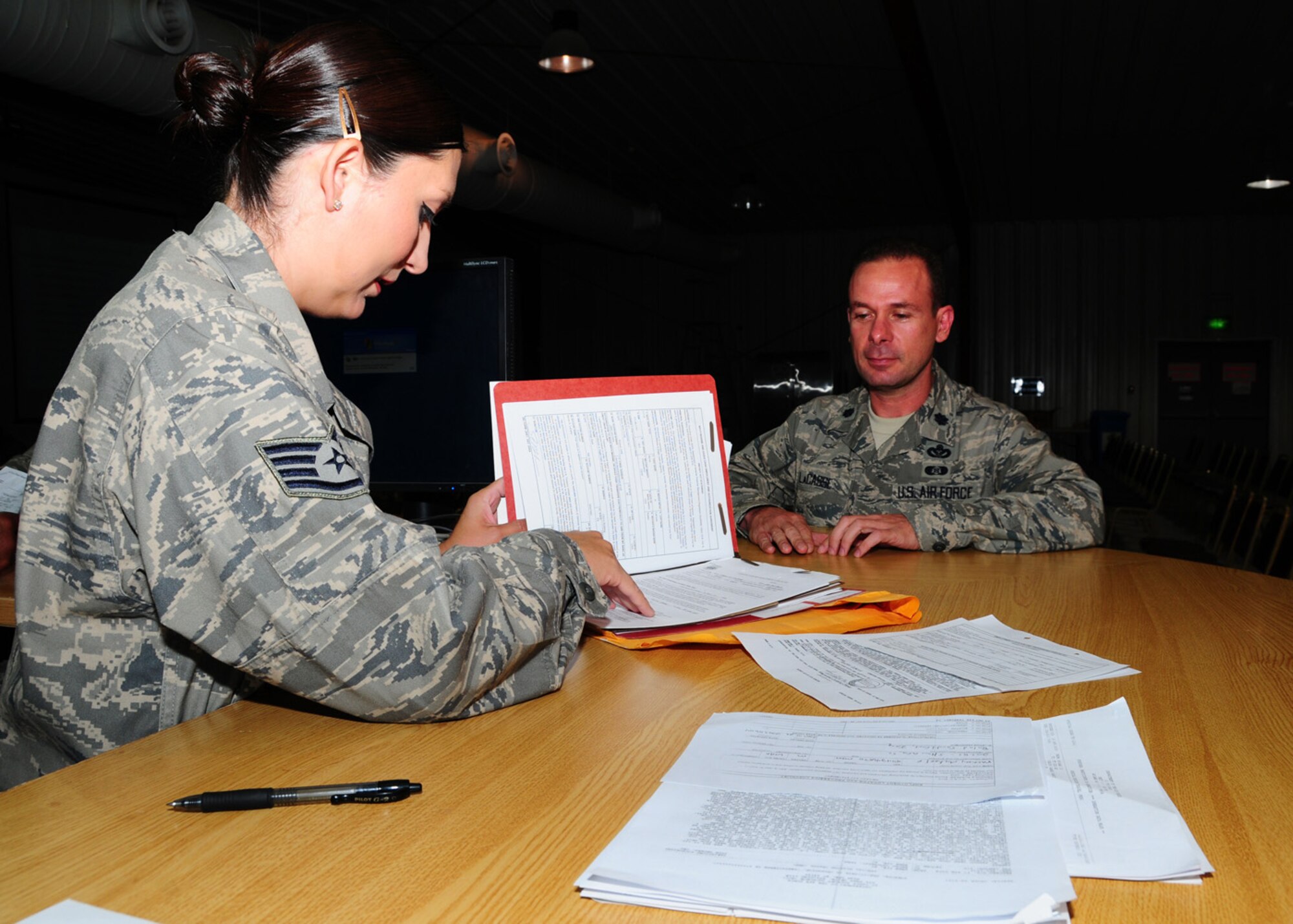 SOUTHWEST ASIA -- Staff Sgt. Amanda Siaosi, 386th Expeditionary Force Support Squadron liaison officer, flips through Lt. Col. Steven Lacasse's mobility folder for a copy of his orders and lodging paperwork at an air base in Southwest Asia, May 29. The responsibility of an Air Force liaison officer is to assist all transient personnel including emergency leave, TDY's, re-deployer and deployer's with temporary lodging and weapons storage until their next flight. Sergeant Siaosi is deployed from Hill Air Force Base, Utah, and is originally from Bernalillo, N.M. Colonel Lacasse is deployed from Hickam Air Force Base, Hawaii, and is deploying to Camp Liberty, Iraq. (U.S. Air Force photo/ Senior Airman Courtney Richardson)