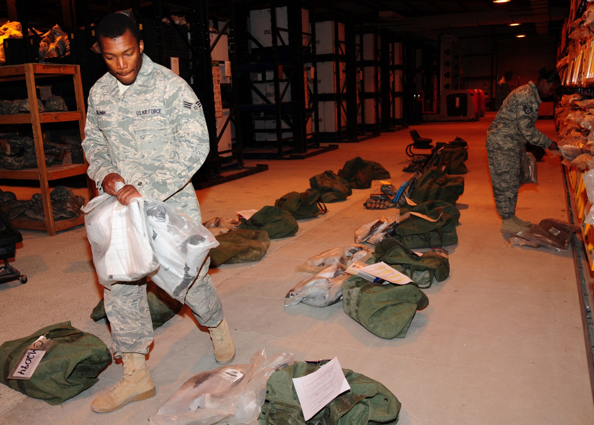 SOUTHWEST ASIA -- Senior Airman Antoine Coleman, 386th Expeditionary Logistics Readiness Squadron, disseminates chemical warfare boots by size to designated bags at the 386th Expeditionary Theater Distribution Center at an air base in Southwest Asia, May 29. Along with issuing mobility equipment, the ETDC provides weapons courtesy storage for Air Force personnel who need to store weapons for the duration of their deployment. Airman Coleman is deployed from Seymour Johnson Air Force Base, N.C., and is originally from Fayetteville, N.C. (U.S. Air Force photo/ Senior Airman Courtney Richardson)