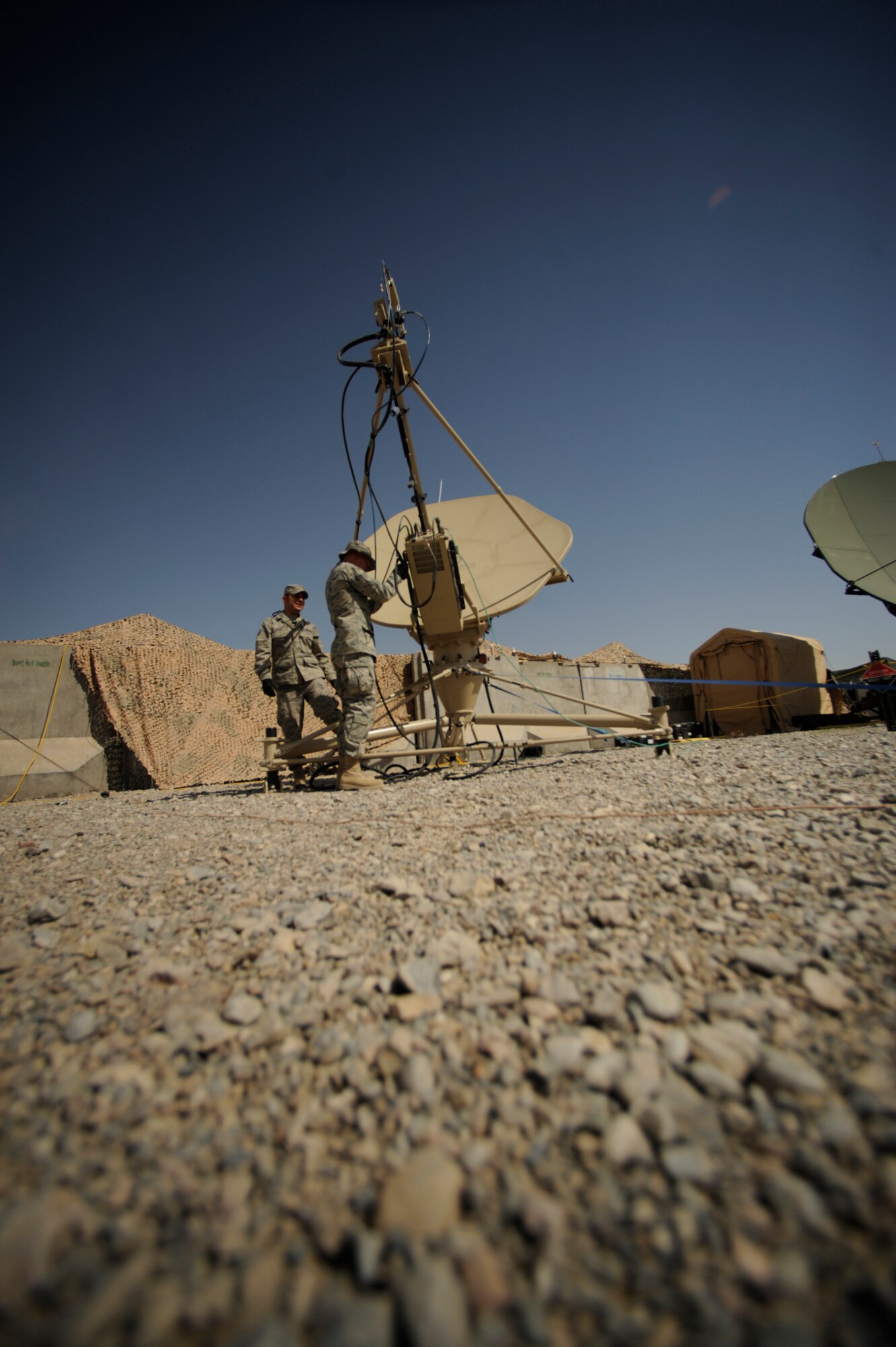 Senior Airman Sergio Saenz and Airman 1st Class Frank Fauland, both satellite communications technicians, 451st Combat Communications Squadron, 451st Air Expeditionary Group, Kandahar Airfield, Afghanistan, conducts routine maintenance on a satellite dish on May 17, 2009, in support of Operation Enduring Freedom.  Combat communications is responsible setting up and maintaining telephone and internet communications to more than 1,500 base users  (U.S. Air Force photo by Staff Sgt. James L. Harper Jr.)