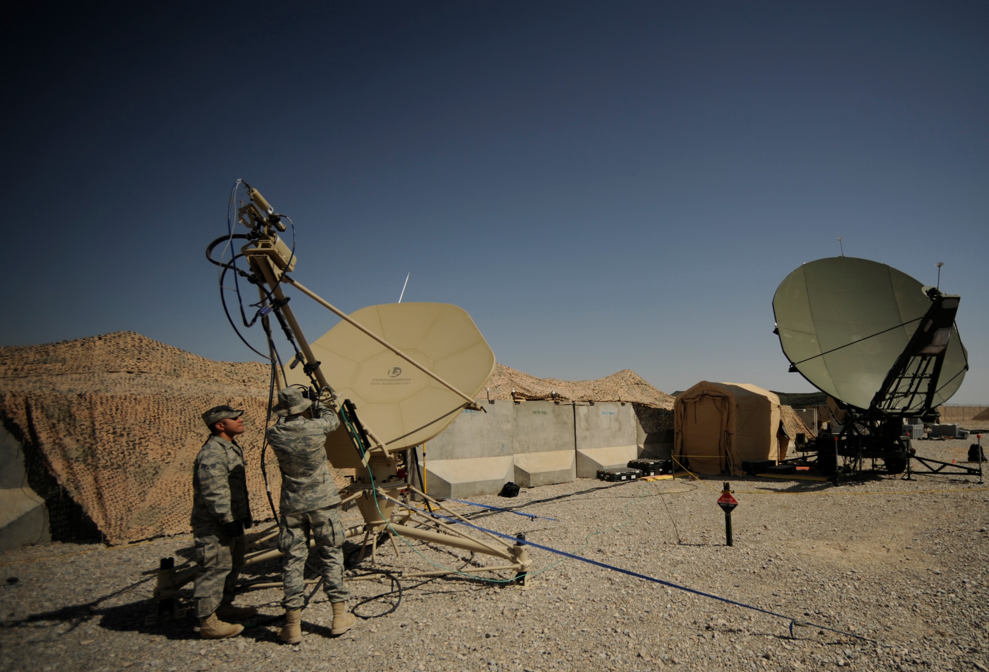 Senior Airman Sergio Saenz and Airman 1st Class Frank Fauland, both satellite communications technicians, 451st Combat Communications Squadron, 451st Air Expeditionary Group, Kandahar Airfield, Afghanistan, conducts routine maintenance on a satellite dish on May 17, 2009, in support of Operation Enduring Freedom.  Combat communications is responsible setting up and maintaining telephone and internet communications to more than 1,500 base users  (U.S. Air Force photo by Staff Sgt. James L. Harper Jr.)