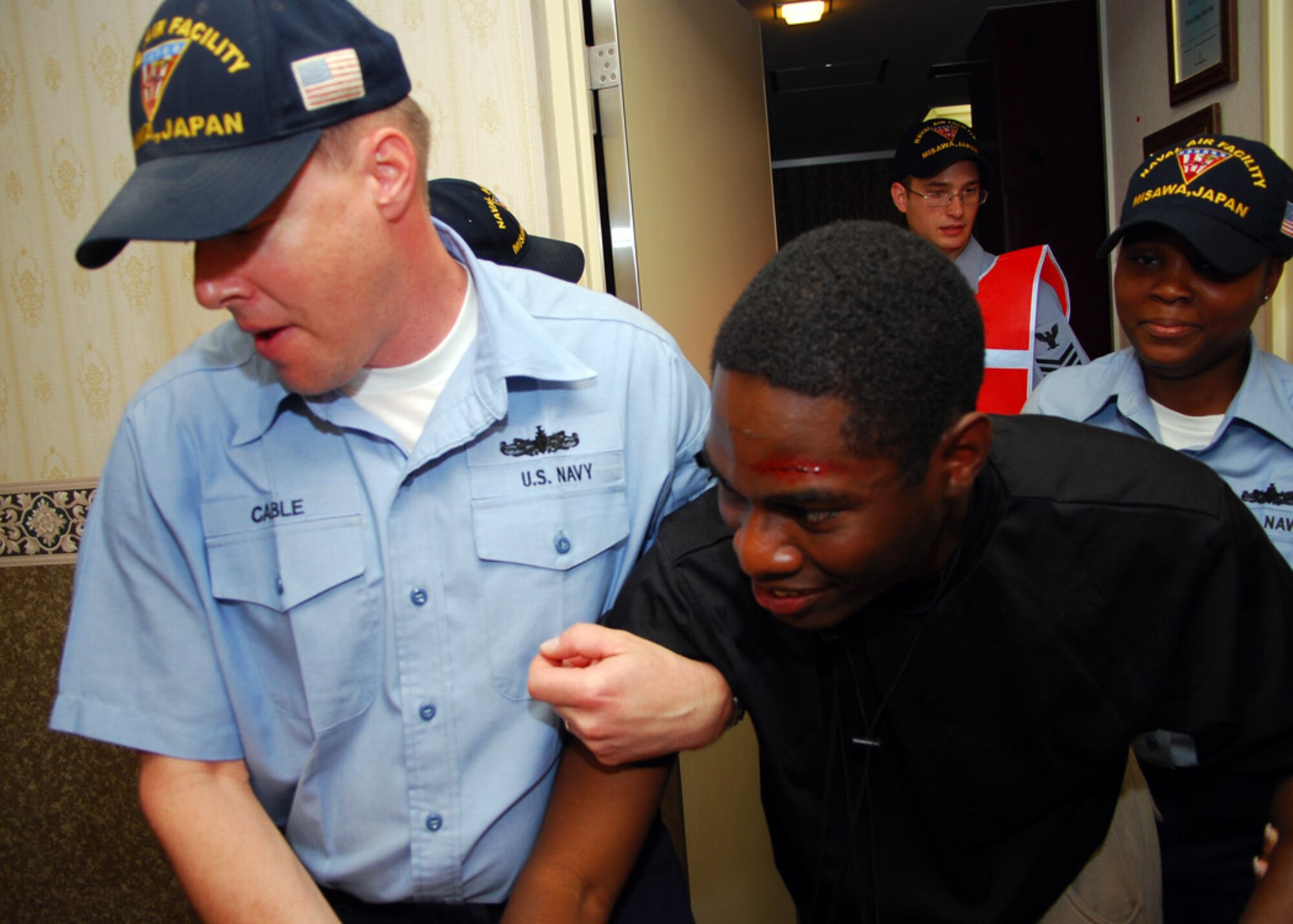 MISAWA AIR BASE, Japan -- Culinary Specialist 1st Class (SW) Randy Cable and Culinary Specialist 2nd (SW) Class Lakita Parker help evacuate a mock casualty from the Navy Gateway Inns and Suites at Naval Air Facility Misawa (NAFM) as Damage Controlman 1st Class (SW) Brandon Kahler, installation training team representative observes June 3, 2009. NAFM held an Installation Training Team/ Regional Training Team assessment drill to hone NAFM?s ability to respond to natural disasters such as earthquakes.  (U.S. Navy Photo by MC2 (SW) Matthew M. Bradley.)