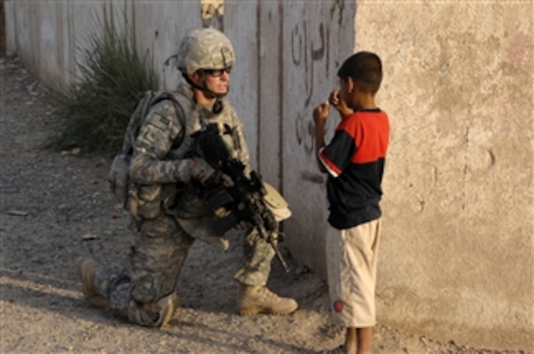 U.S. Army Sgt. Jason Reese, with Delta Company, 2nd Battalion, 112th Infantry Regiment, 56th Stryker Brigade Combat Team, speaks to a young Iraqi boy during a joint patrol with Iraqi police through a village in the Abu Ghraib district of Baghdad, Iraq, on May 26, 2009.  