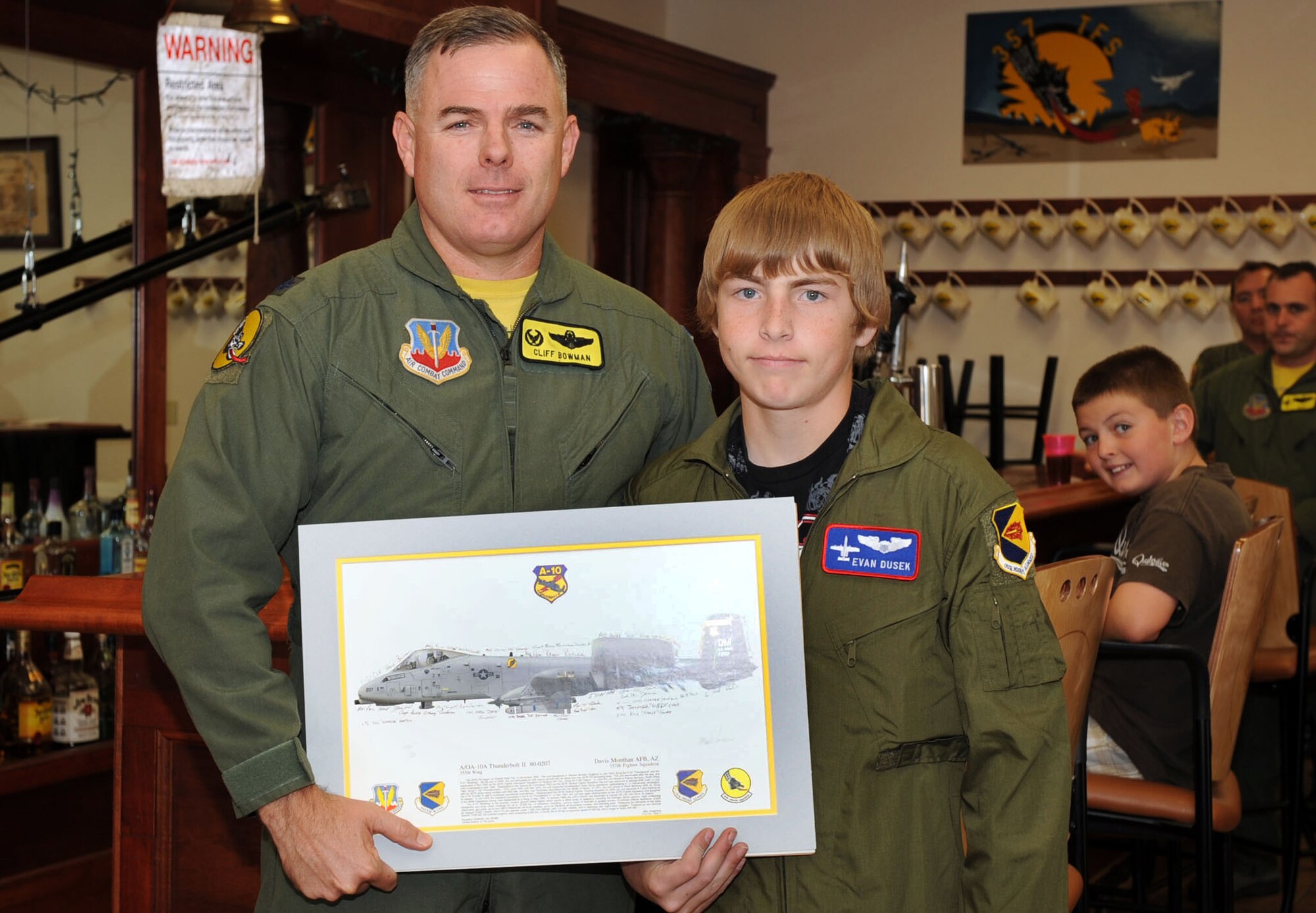 Lt. Col. Clifford Bowman, 357th Fighter Squadron commander, presents Evan Dusek, May Pilot for a Day, with a photo of an A-10, signed by several pilots from the squadron.  (U.S. Air Force photo/Airman 1st Class Brittany Dowdle)