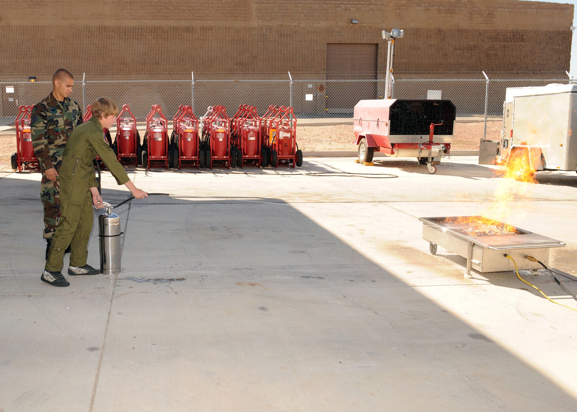 Staff Sgt. Anthony Stanchfield of the 355th Civil Engineer Squadron shows Evan Dusek the proper way to put out a fire with a fire extinguisher during his Pilot for a Day visit here May 29.  (U.S. Air Force photo/Airman 1st Class Brittany Dowdle)