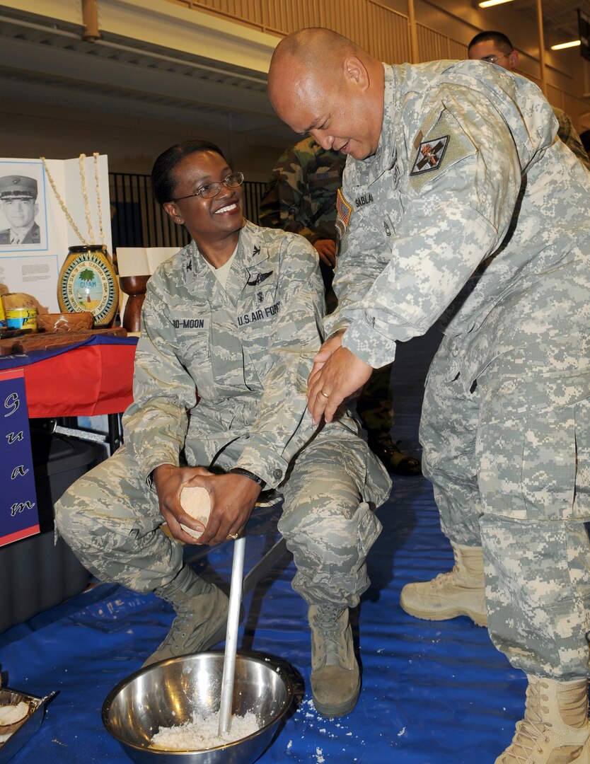 Col. Soledad Lindo-Moon, 12th Medical Group commander, and Army Sgt. 1st Class James Sablan, Brooke Army Medical Center, work together to grind coconut in the traditional Guamanian fashion during the festival. (U.S. Air Force photo by Don Lindsey)