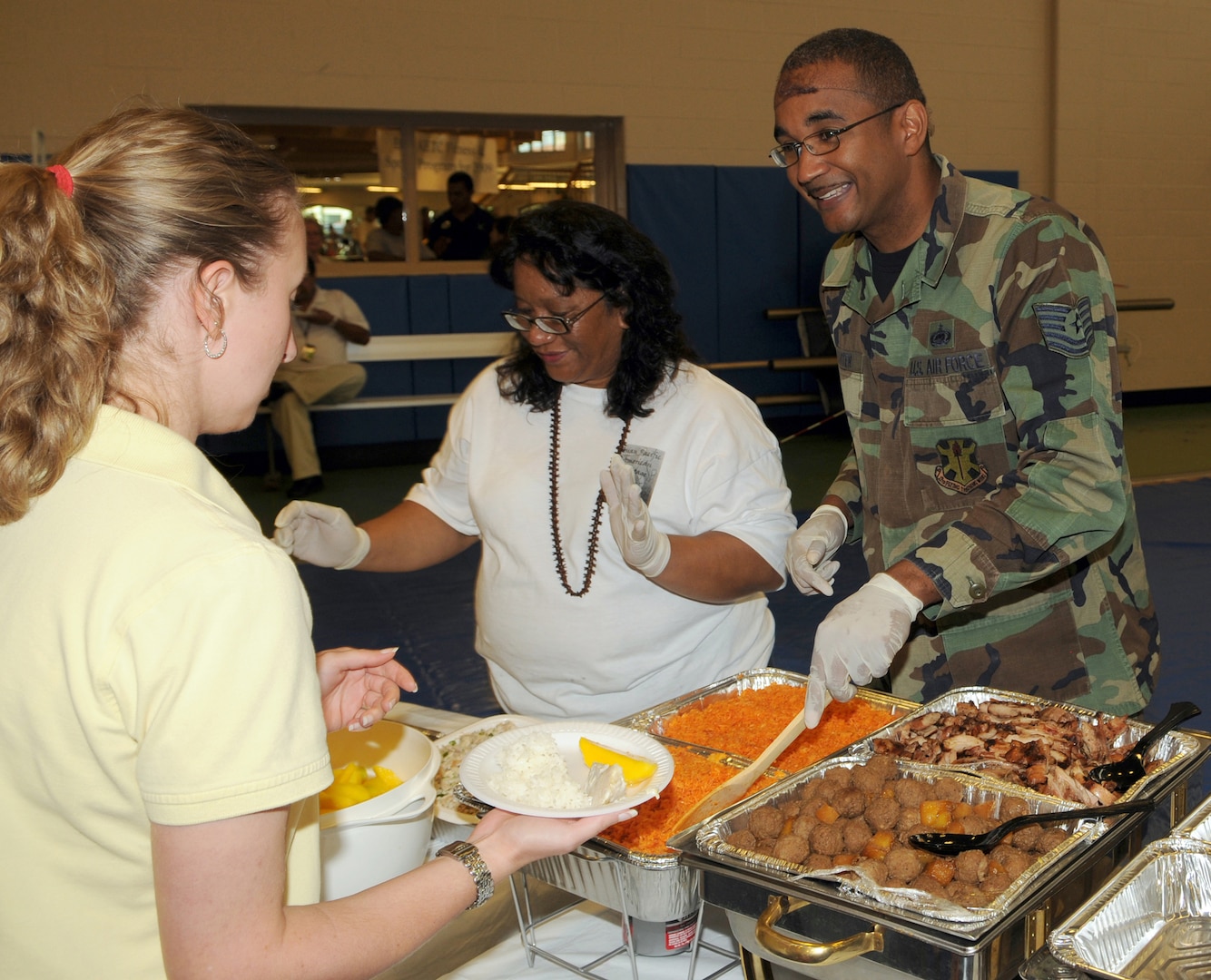 Judy Diaz, 12th Mission Support Group Civil Engineer Division, and Tech. Sgt. Carlos Barter, 12th Flying Training Wing Equal Opportunity Office, serve up some Asian Pacific American cuisine at the fitness center on May 27. (U.S. Air Force photo by Don Lindsey)