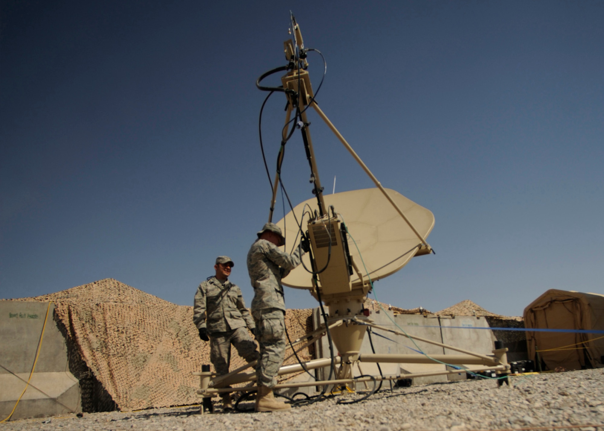 Senior Airman Sergio Saenz and Airman 1st Class Frank Fauland perform routine maintenance May 17 on a satellite dish at Kandahar Airfield, Afghanistan. Combat communications Airmen are responsible setting up and maintaining base telephone and internet communications.  The Airmen are RF transmissions engineers and satellite communications technicians with the 451st Combat Communications Squadron at Kandahar.   (U.S. Air Force photo/Staff Sgt. James L. Harper Jr.)