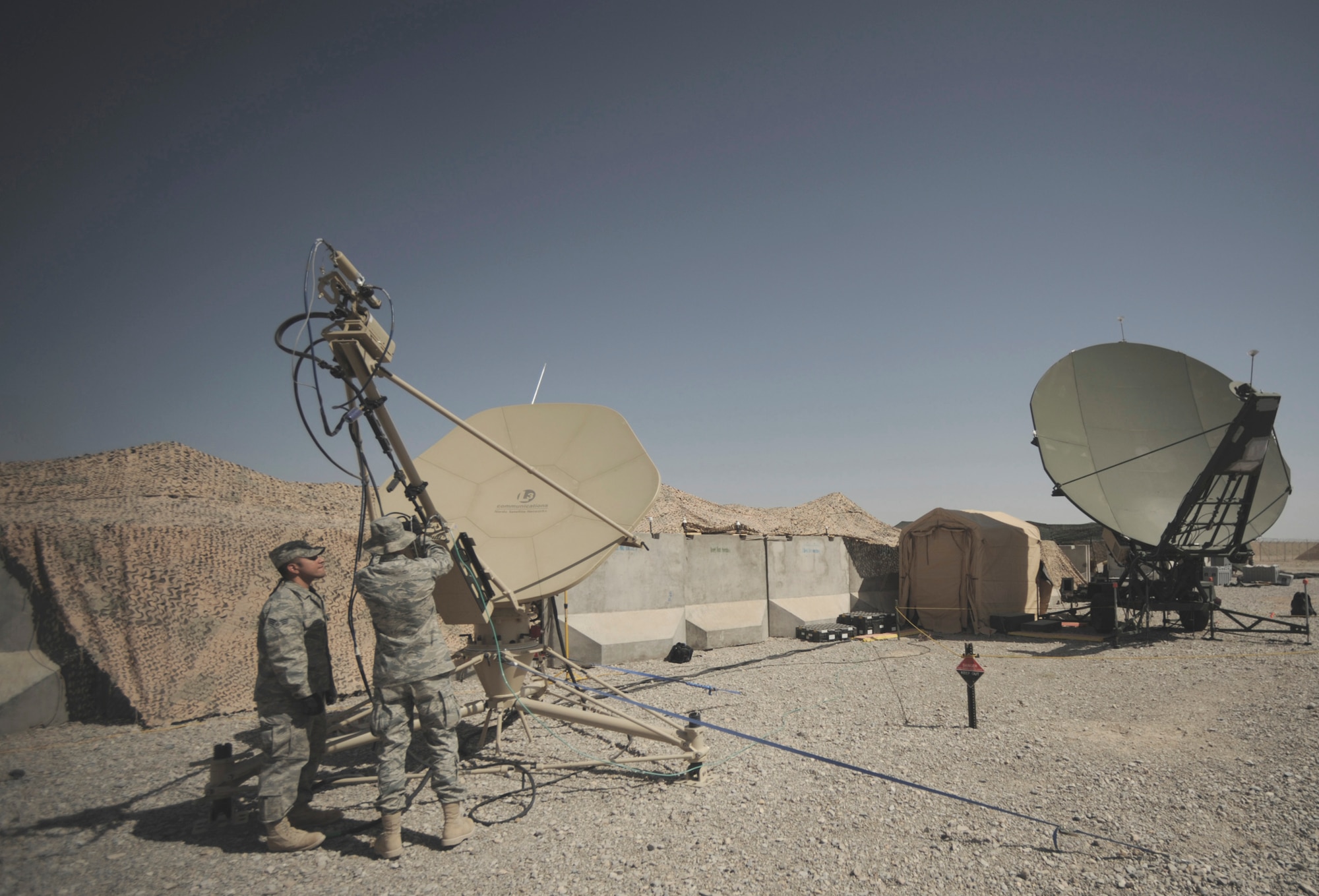 Senior Airman Sergio Saenz and Airman 1st Class Frank Fauland perform routine maintenance May 17 on a satellite dish at Kandahar Airfield, Afghanistan. Combat communications Airmen are responsible setting up and maintaining base telephone and internet communications.  The Airmen are RF transmissions engineers and satellite communications technicians with the 451st Combat Communications Squadron at Kandahar.   (U.S. Air Force photo/Staff Sgt. James L. Harper Jr.)