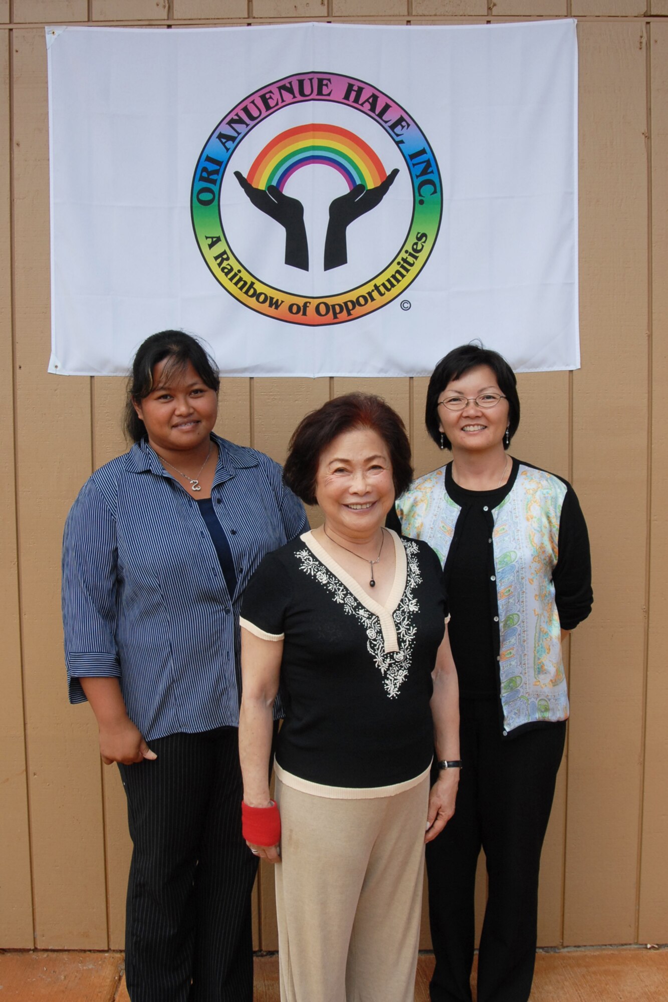 Susanna Cheung (center), president and founder of Opportunities For the Retarded (ORI) Anuenue Hale, stands under her company’s slogan in front of the Helemano Plantation’s Elderly Day Care/Wellness Center with employees May Isnec (left) and Ann Siga (right). The center provides offers several senior citizen services, including medical assistance, yoga classes, computer lessons, and other helpful amenities and activities. (USAF photo by SrA. Anna-Marie Wyant
