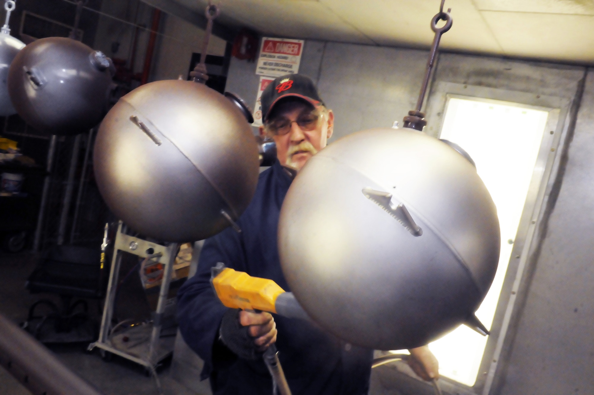 Gary Henderson applies a powder coating finish on fire bottles. U. S. Air Force photo by Sue Sapp