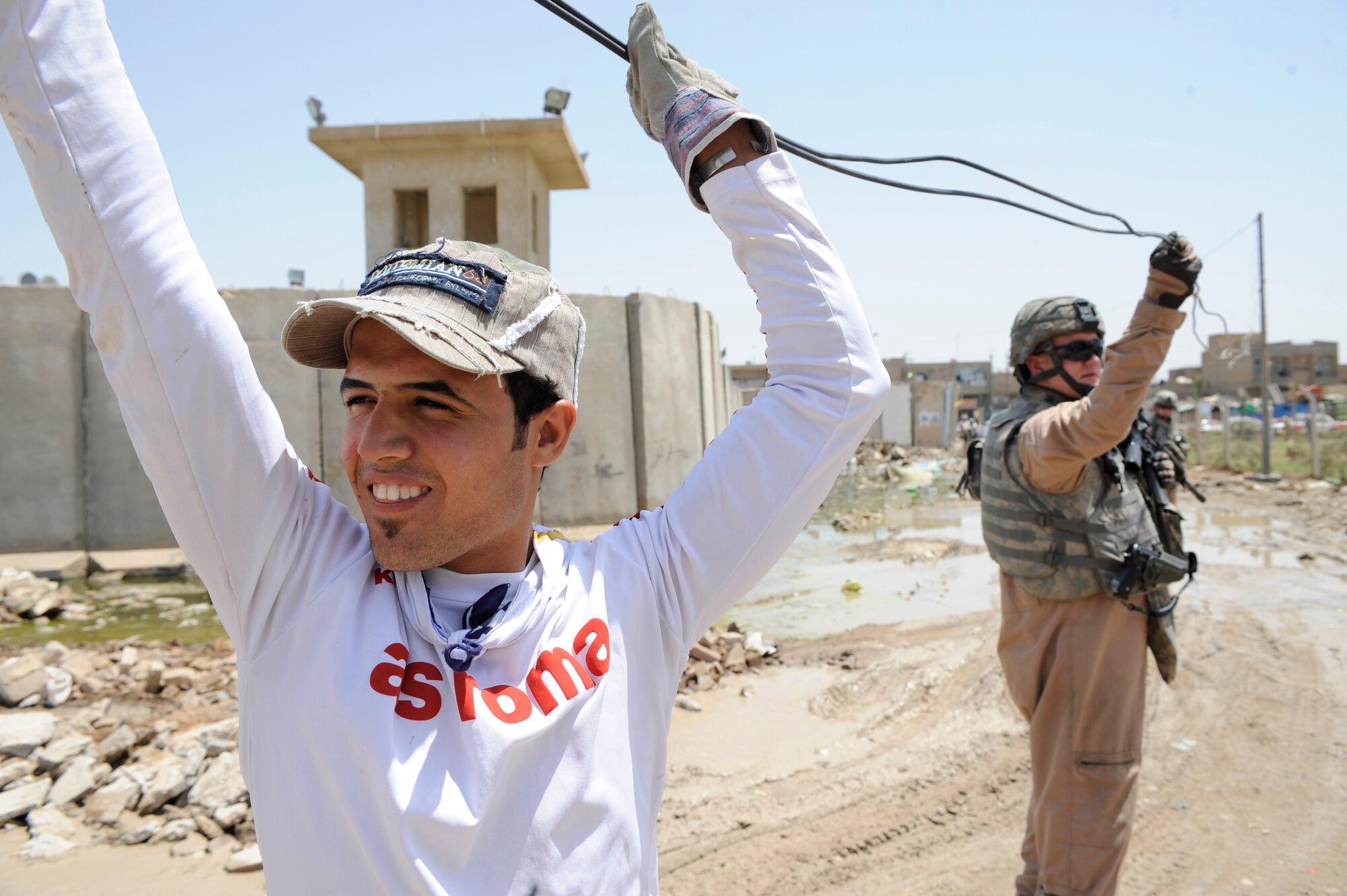 A U.S. Air Force Airman of the 732nd Expeditionary Security Forces Squadron Det. help a local electrician May 12, 2009, in Baghdad. (U.S. Air Force Photo by Staff Sgt. Shawn Weismiller)