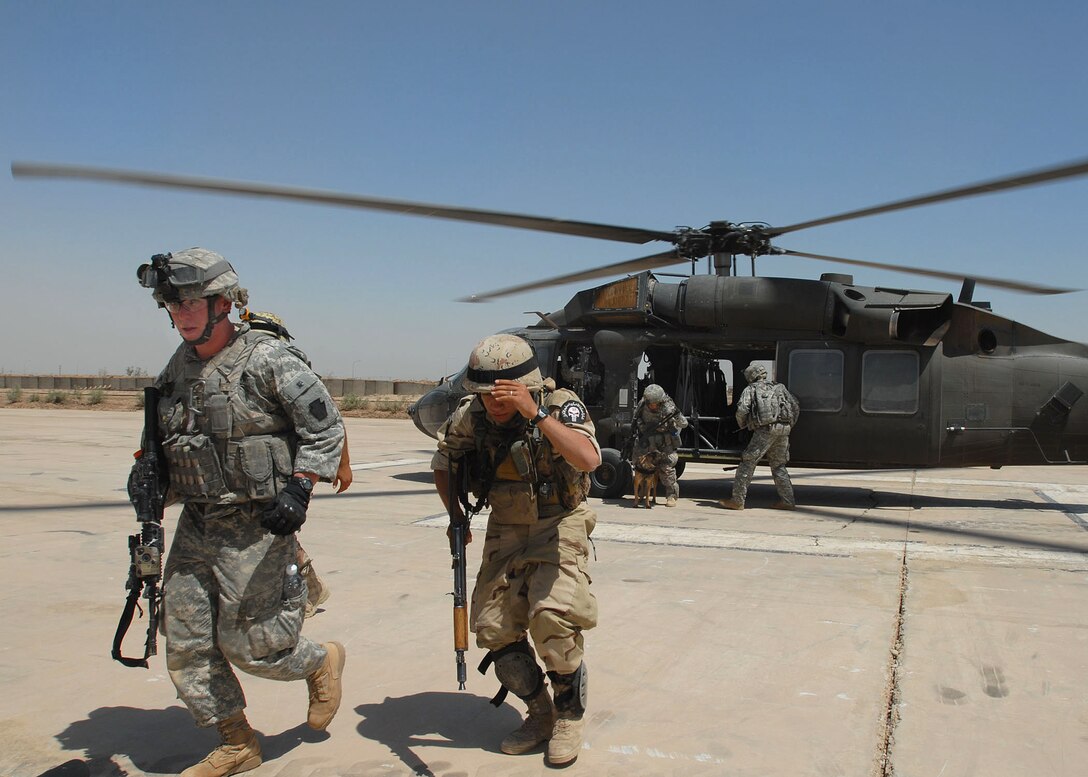 U.S. Army Spc. Elam Scott, left, and an Iraqi soldier leave a helipad after completing a mission on Camp Taji, Iraq, June 3, 2009. Scott is assigned to Headquarters Company, 1st Battalion, 112th Infantry Regiment.