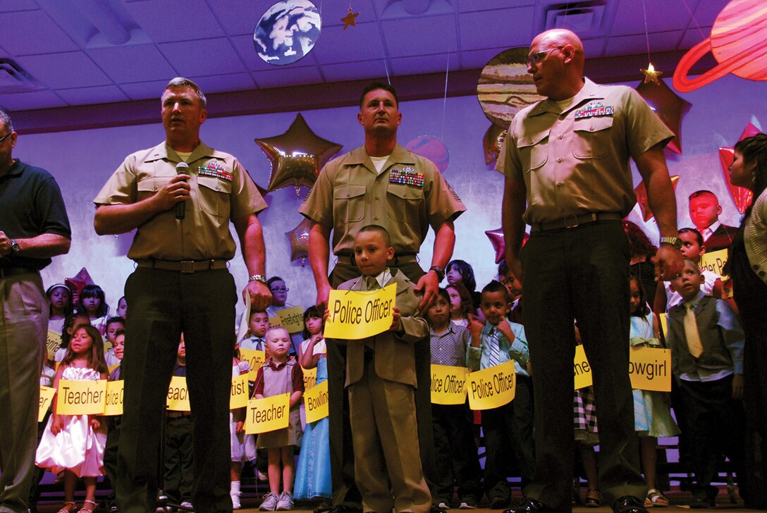 Alan Gonzalez Jr. stands with three Yuma explosive ordnance disposal Marines at his Harvest Preparatory Academy kindergarten graduation in Yuma, Ariz., June 4, 2009. Chief Warrant Officer 2 Simon Wade, left, Marine Wing Support Squadron 371 EOD officer in charge, attended the graduation at the request of Gonzalez’s stepfather, Staff Sgt. Alonzo Smith, MWSS-371 EOD technician, who was wounded May 26, 2009, while disarming an improvised explosive device in Afghanistan.(Photo by Lance Cpl. Graham J. Benson)