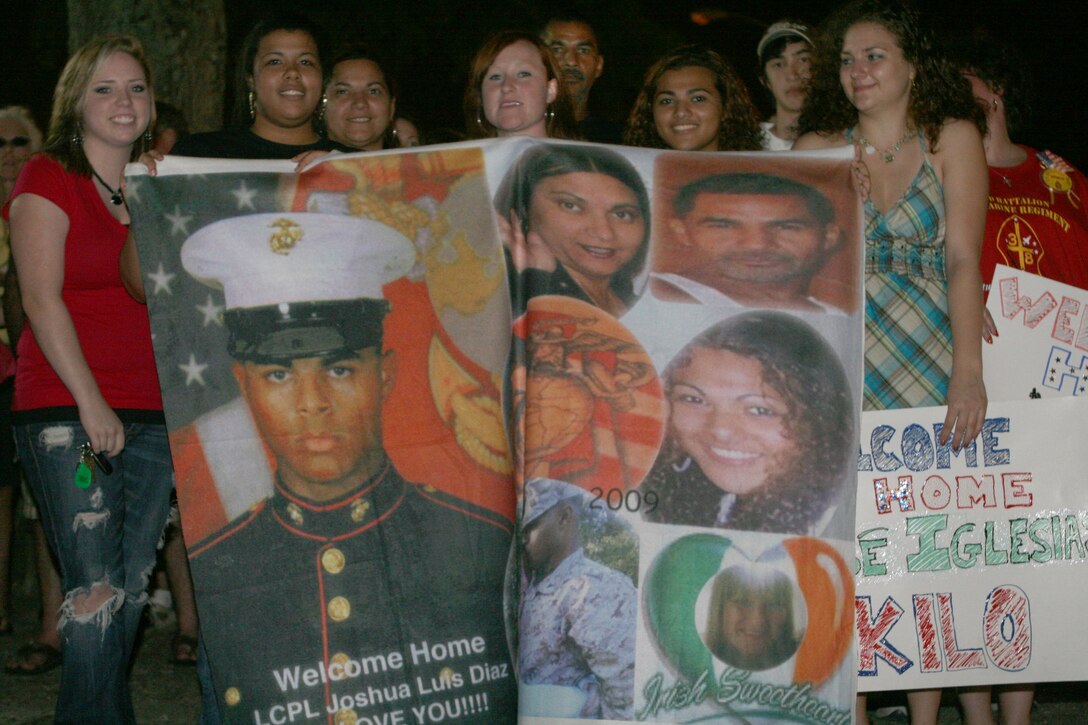 Friends and family hold a mural of Lance Cpl. Joshua L. Diaz, Company I, 3rd Battalion, 8th Marine Regiment, 2nd Marine Division, while welcoming the Marines home from their deployment to Afghanistan, June 4. (U.S. Marine Corps Photo by Lance Cpl. James W. Clark)(RELEASED)