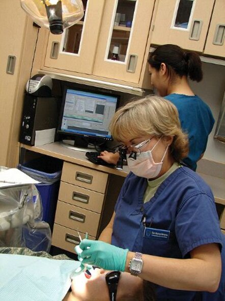 Col. Nancy Motyka, residency director of Advanced Education in General Dentistry, performs a dental examination of a patient while Dental Technician A1C Irma Gonzalez makes on-screen treatment notes in the AHLTA program.