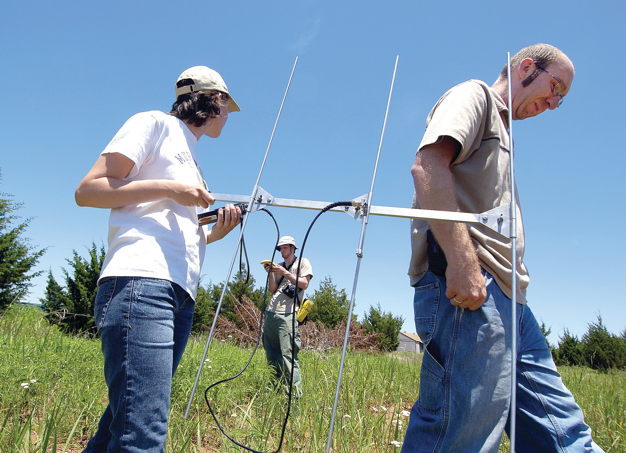 Victor Bogosian, a PhD researcher from Southern Illinois University, and student conservation associates Katie Hietz and Jeffrey Ackley move slowly through the high grasses behind base housing using the beeping of their transponder to locate tagged Texas Horned Lizards. The pea-sized transmitters each tagged lizard wears help scientists learn about the animal listed as a state species of “special concern,” a protection researchers want to keep from moving to “threatened” or “endangered.” (Air Force photo/Margo Wright)