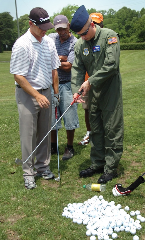 Jason Schultz, a professional golfer, helps Master Sgt. Christopher King, 99th Airlift Squadron flight engineer, with his grip during the free golf clinic at The Courses at Andrews Tuesday. (U.S. Air Force photo/ Bobby Jones)