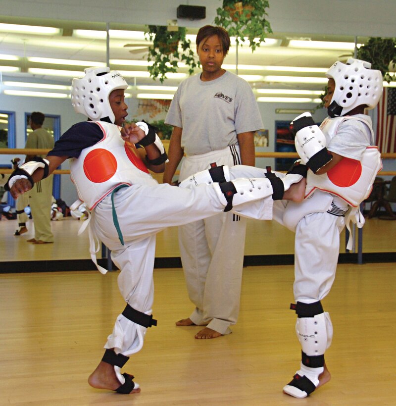 Aaron Posey, 8,left, and Jacquez Booker, 7, engage simultaneously with front thrust kicks as LaShondra Rawls, an assistant Tae Kwon Do instructor and 2nd degree black belt, observes during a junior class at Master Love’s Tae Kwon Do class held at the Youth Center recently. Aaron is is the son of Master Sgt. Regina Posey, National Recognizance Organization superintendent of military personnel, Ft. Belvoir, Va. Jacquez is the son of Navy Chief Petty Officer Shaun Booker, Fleet Logistics Squadron 48 administration chief.  (U.S. Air Force photo/ Bobby Jones)